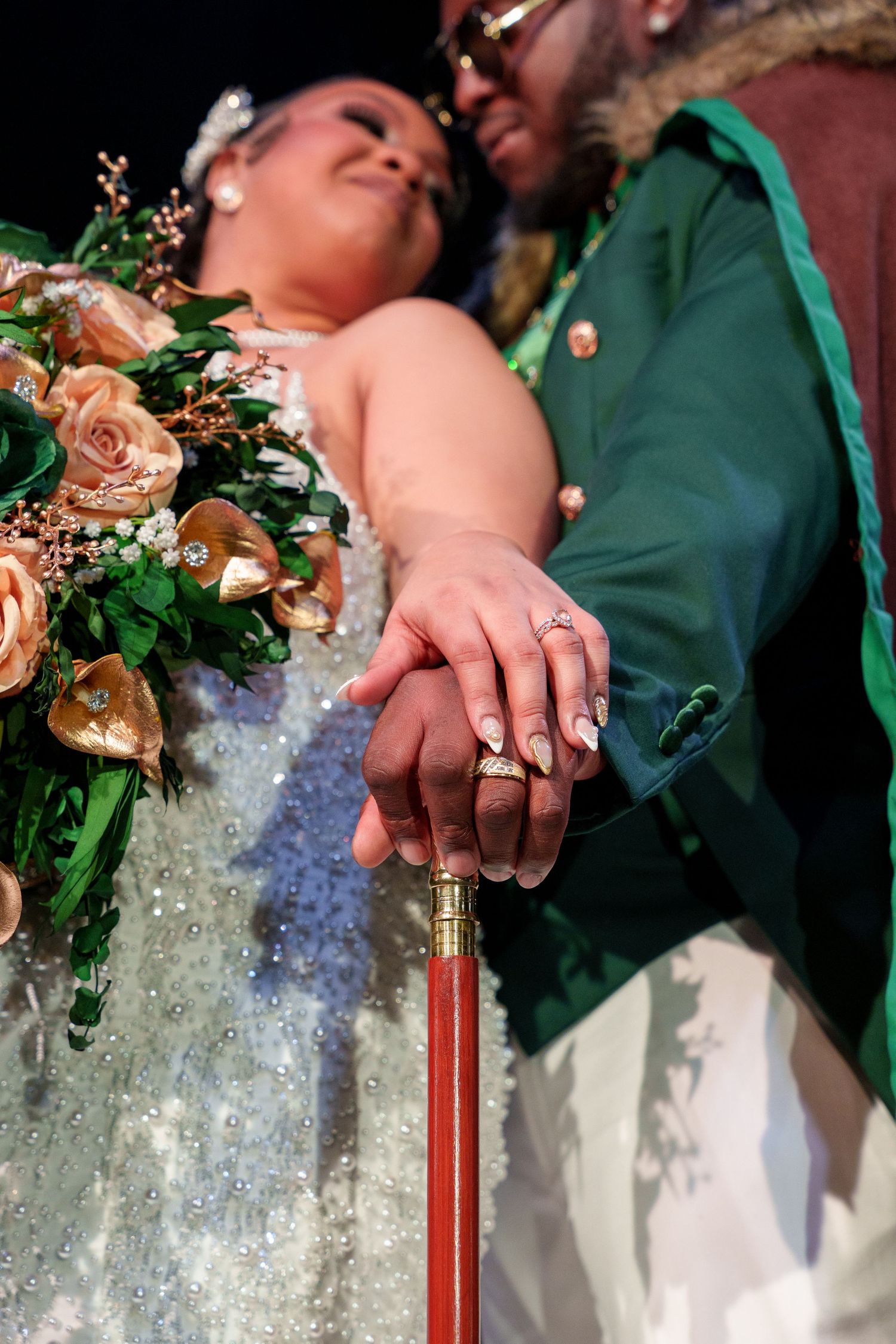 Close-up of wedding rings and floral bouquet with peach roses.