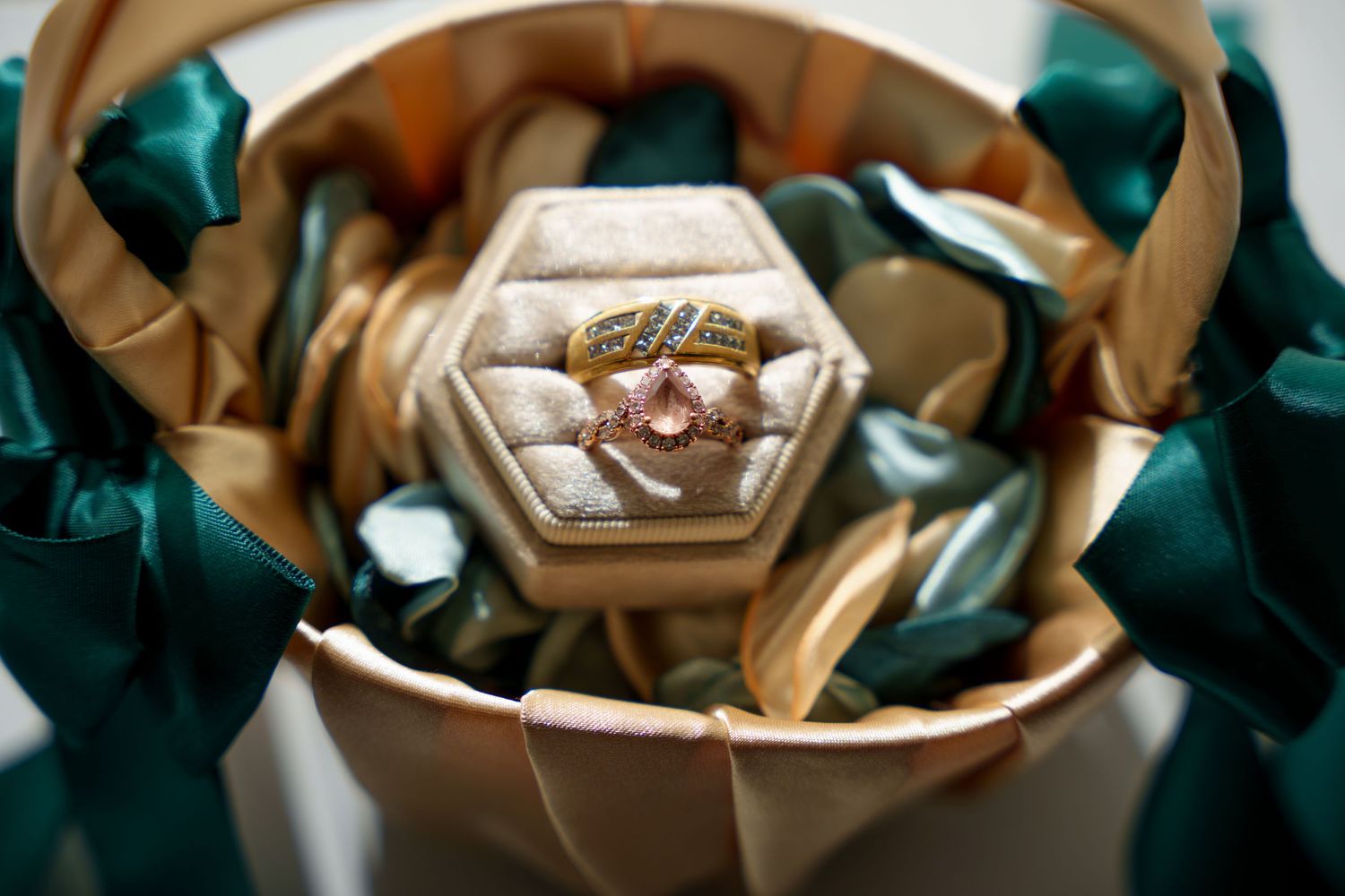 Wedding ring nestled in hexagonal box with emerald green and gold fabric details.
