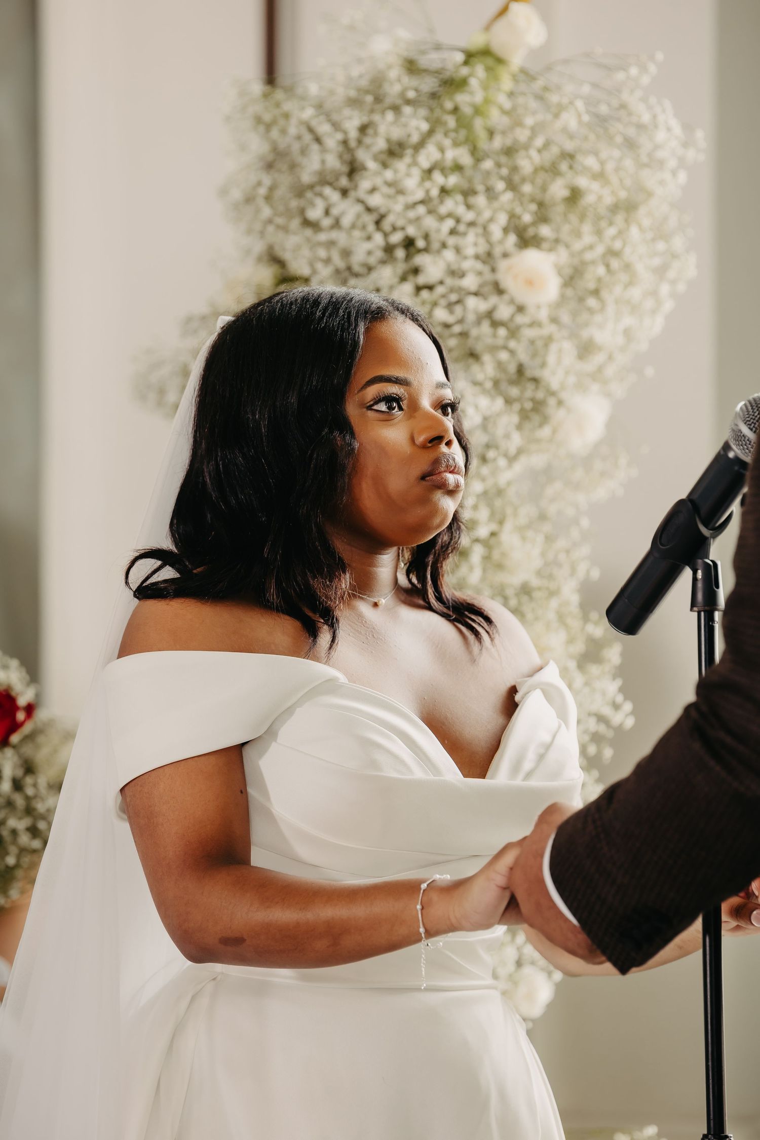 A wedding ceremony moment with an off-shoulder white dress and baby's breath floral decorations.