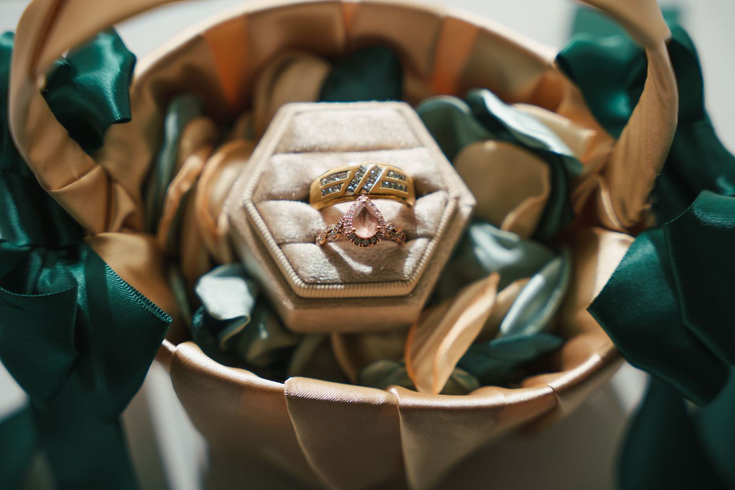 Wedding rings displayed on emerald green silk fabric with elegant details.