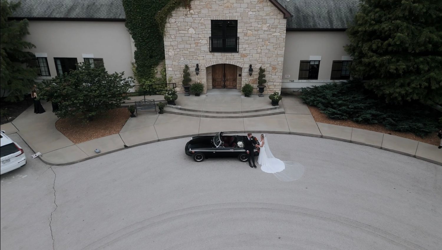 Rustic outdoor wedding venue with thatched roof buildings and stone pathways.