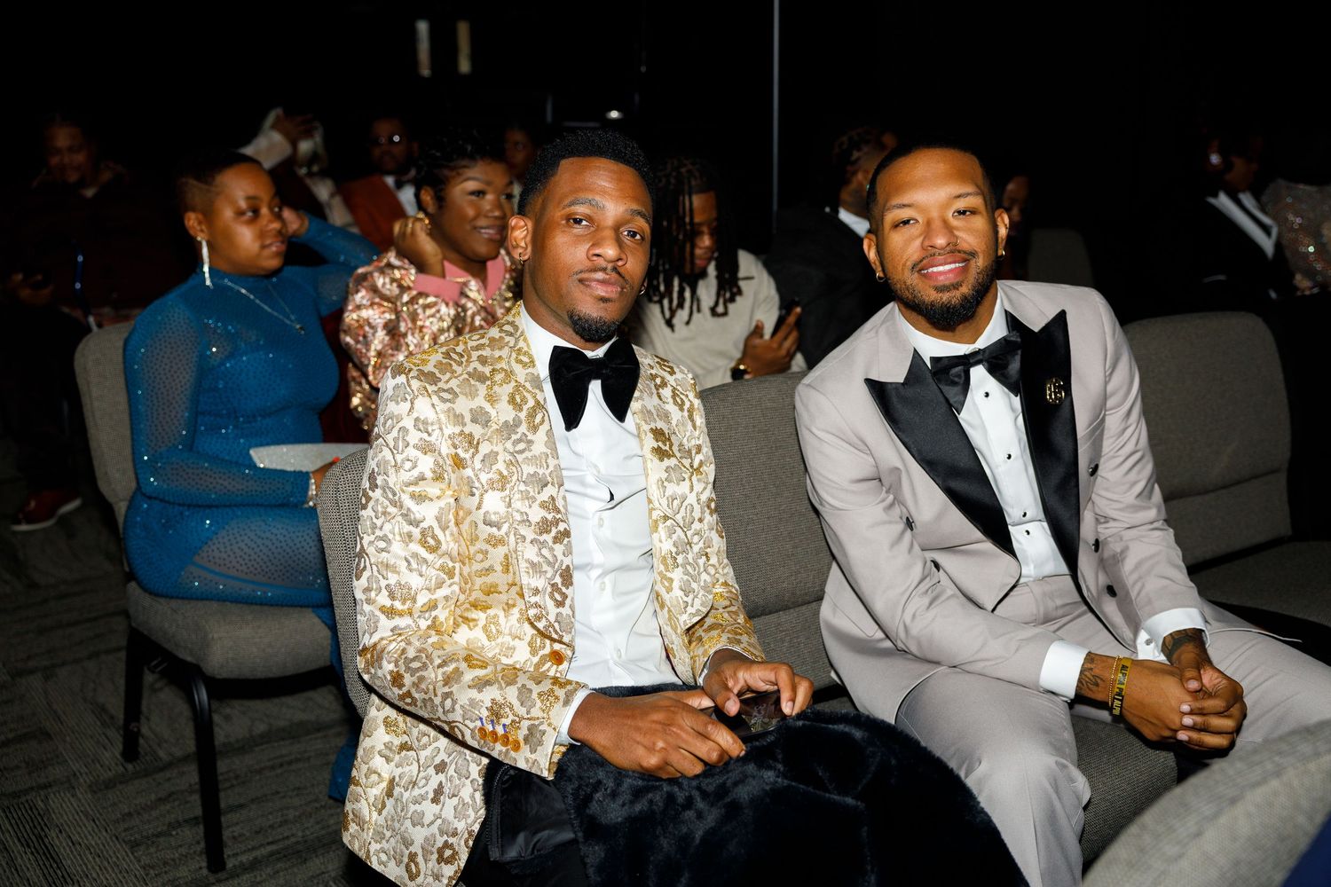 Wedding guests in formal attire including gold sequined jacket seated at reception.