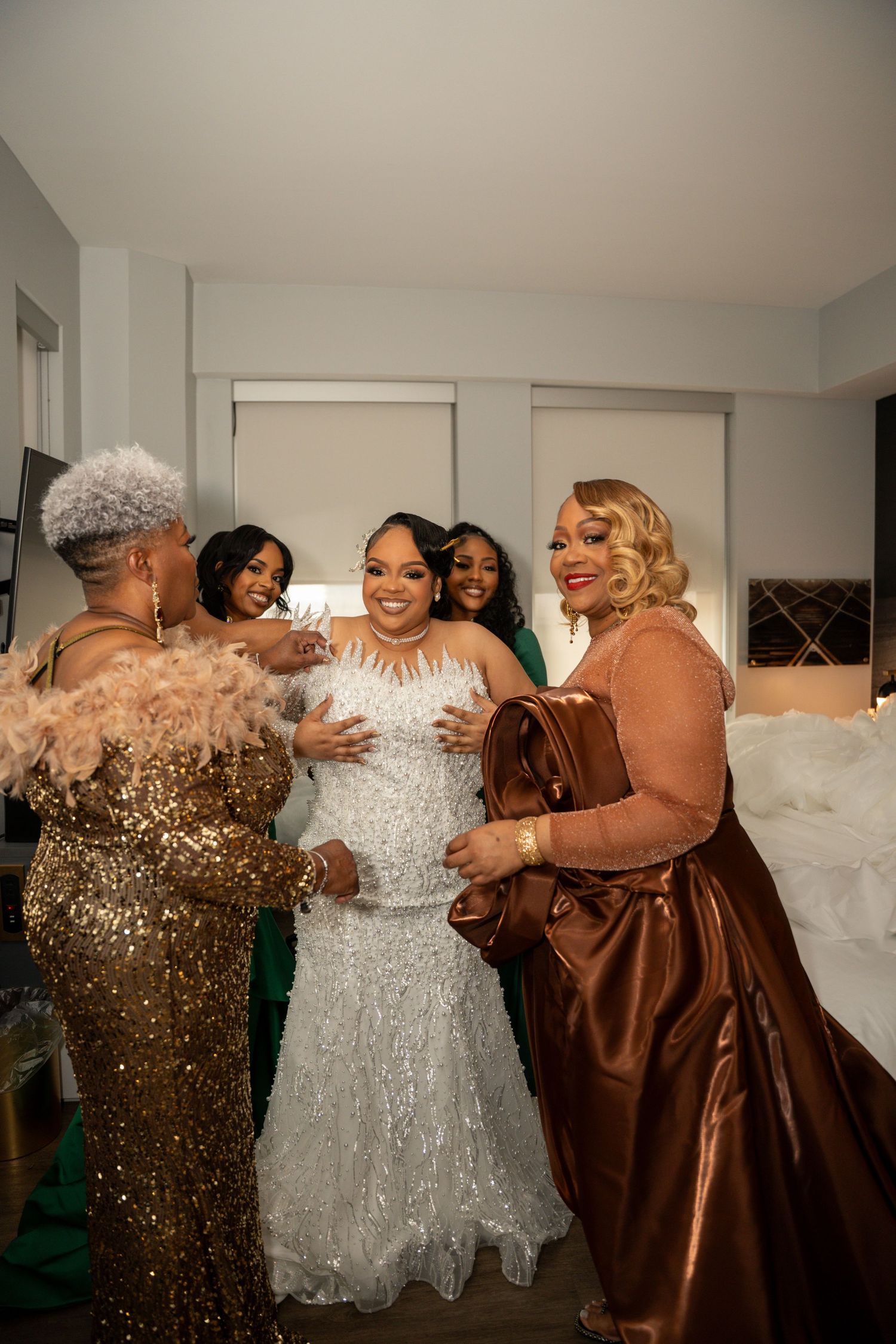 Wedding party members in brown and white dresses share an emotional embrace during celebration.