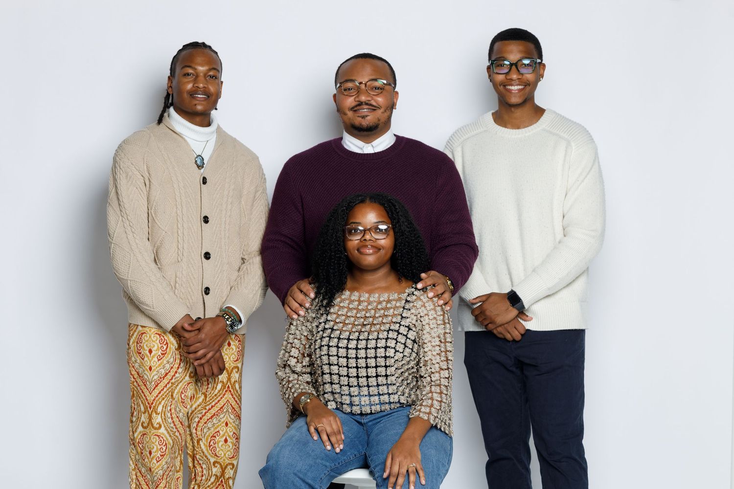 Group portrait against white background wearing coordinated casual outfits in neutral tones.