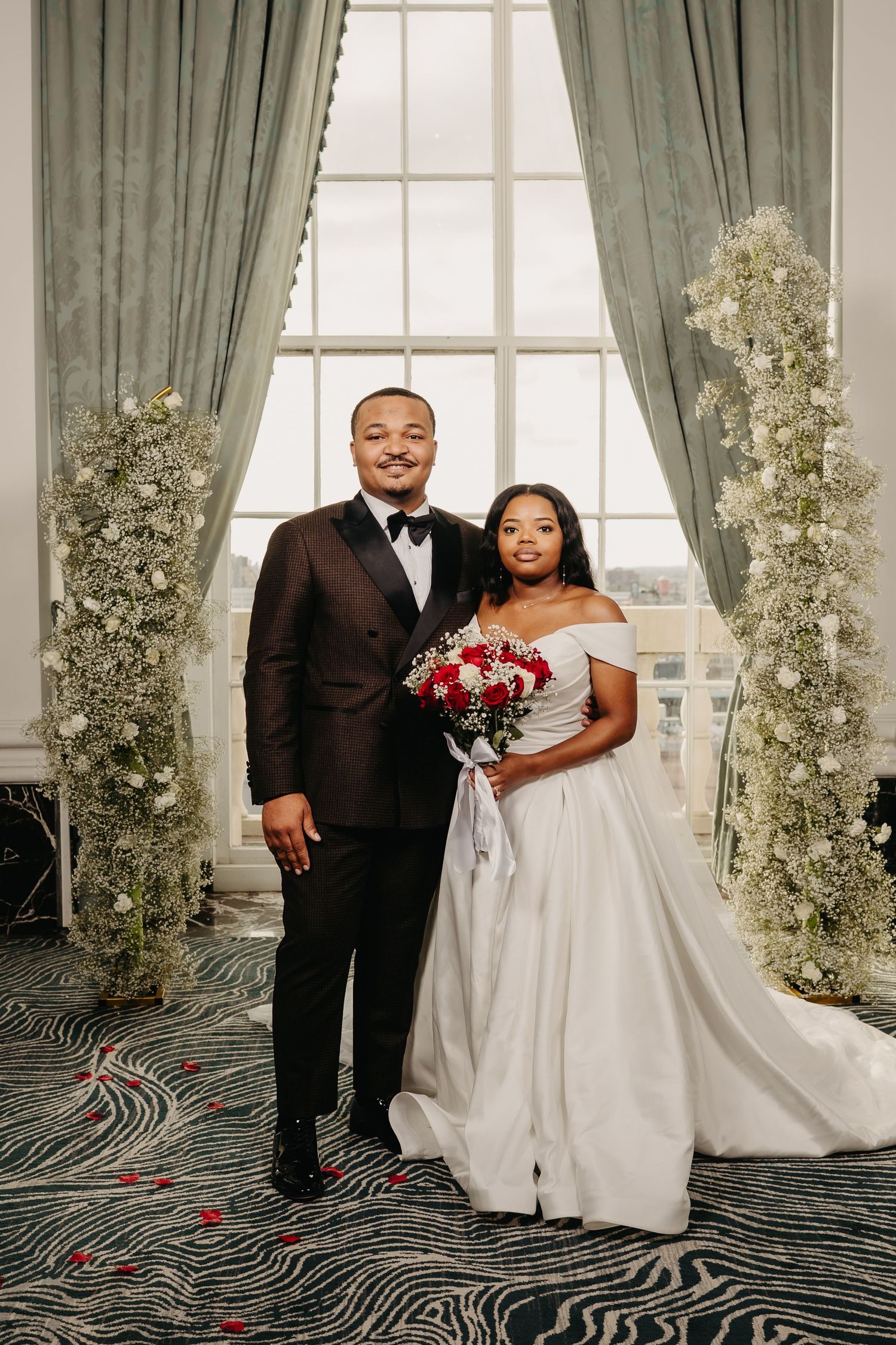 Elegant wedding portrait in front of windows with sage green curtains and baby's breath floral arrangements.