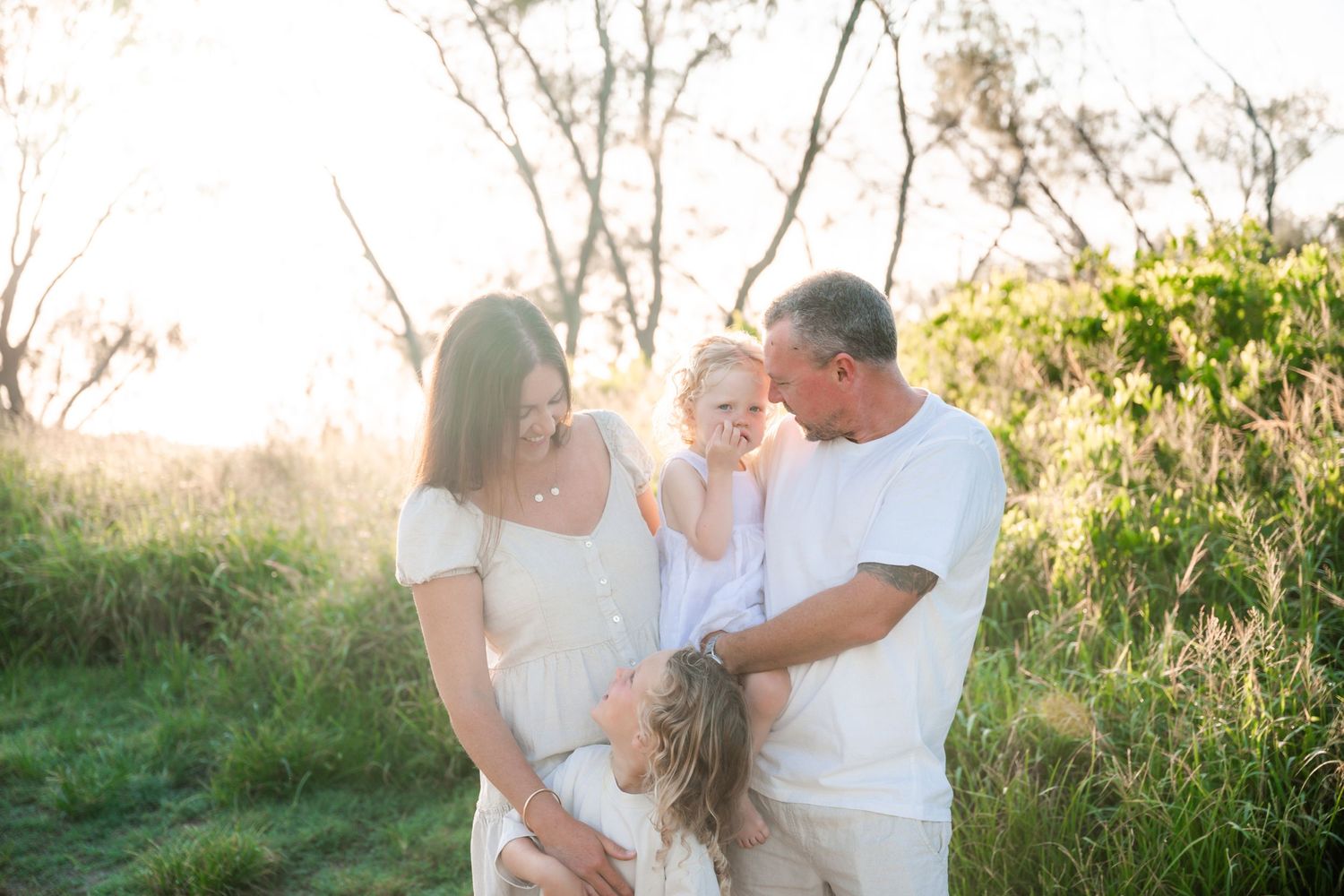 Family cuddling at Kingscliff during a sunrise session with Wonderland Photography.