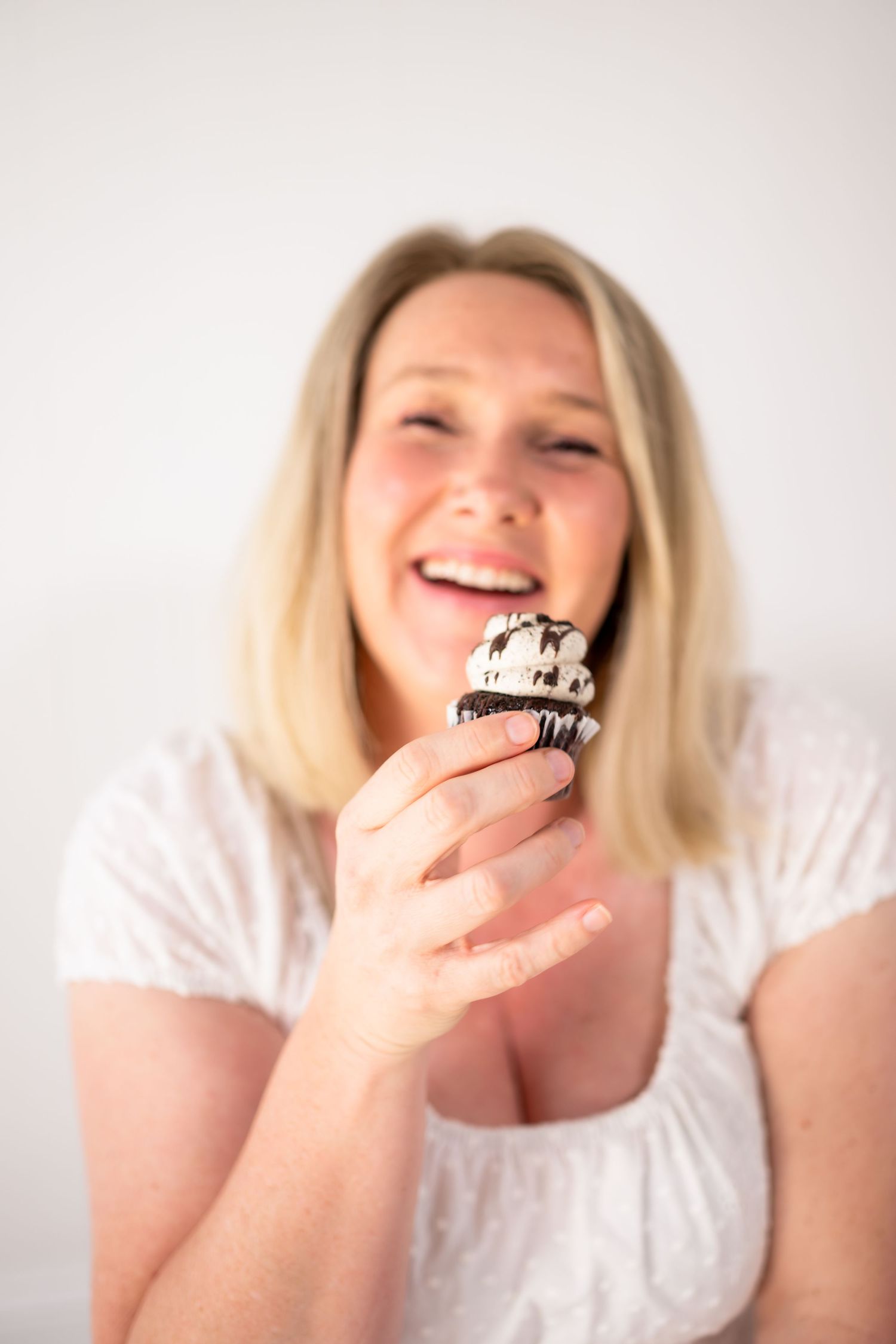 Wonderland Photography holding a cupcake and laughing in studio at Banora Point