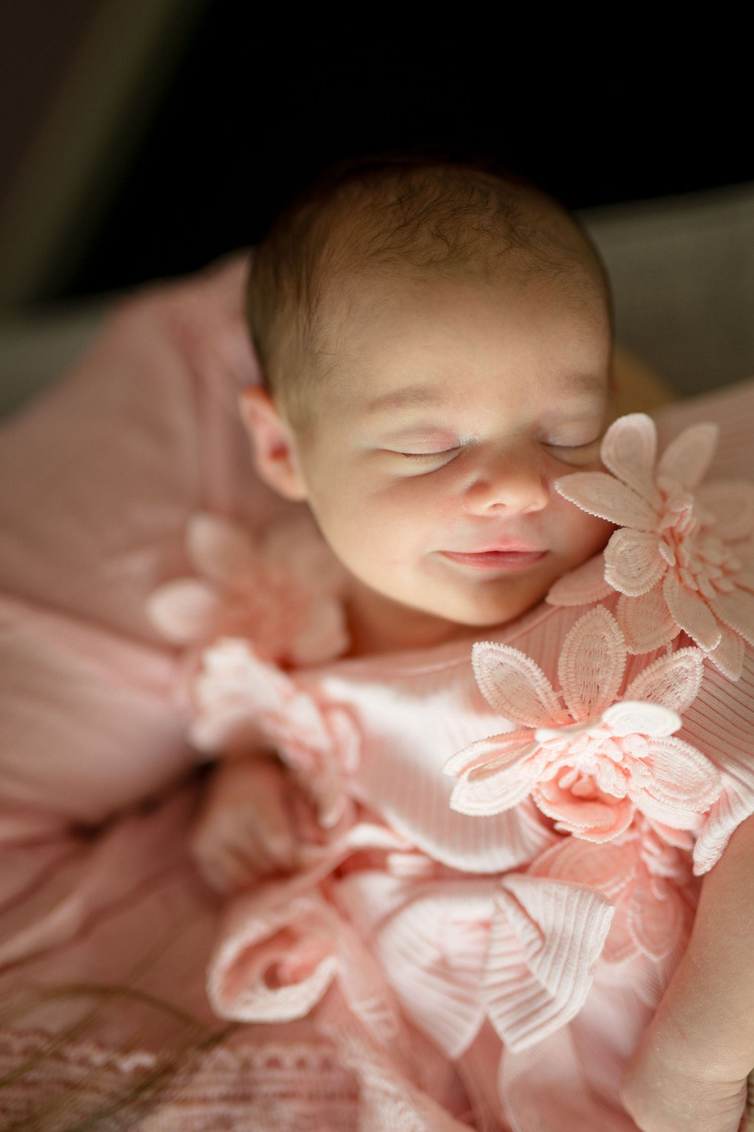 Delicate pink butterflies and floral decorations create a dreamy overlay effect on a sleeping baby in soft lighting.