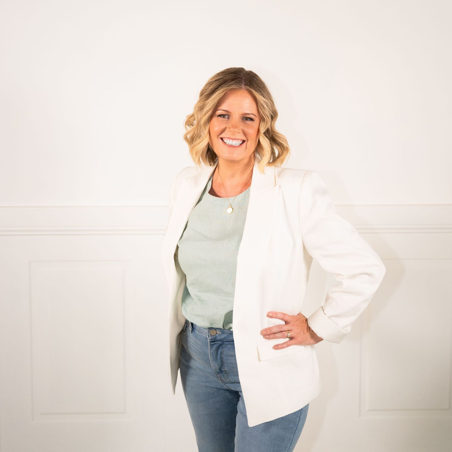 Woman in casual attire smiling and posing against white background in professional photography series.