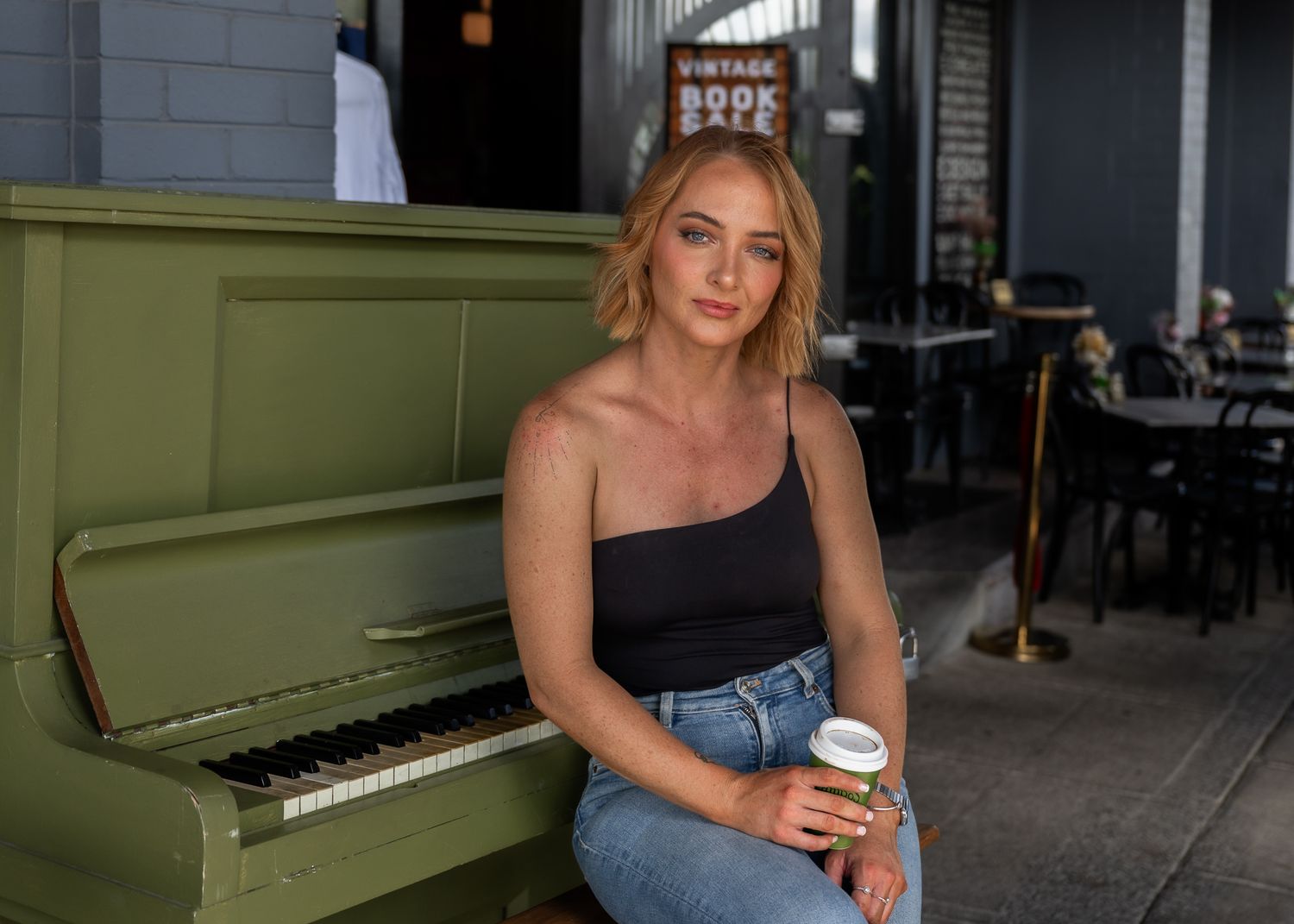 Vintage green piano against industrial brick wall in urban setting, personal branding shoot with Wonderland Photography