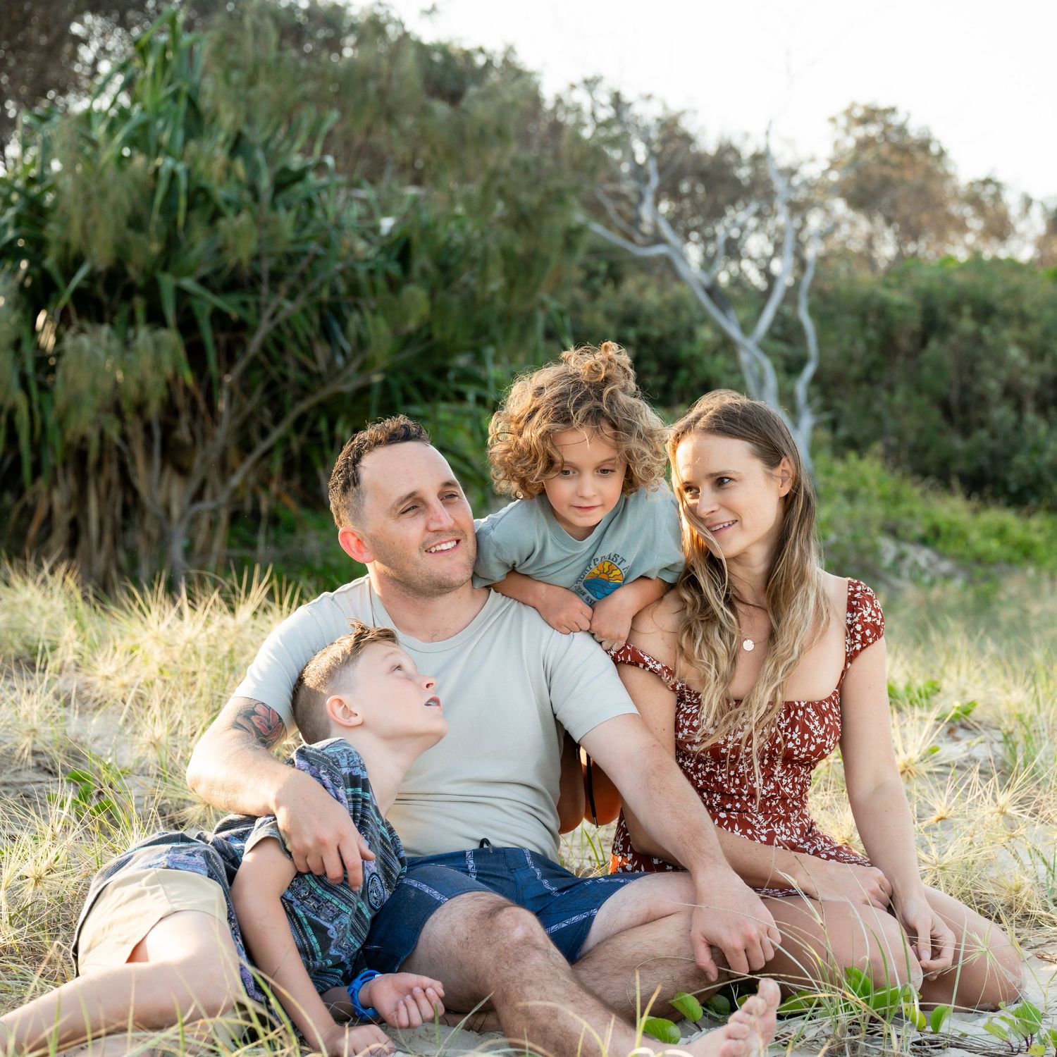 Family cuddling at Cabarita Beach during a golden hour session with Wonderland Photography.