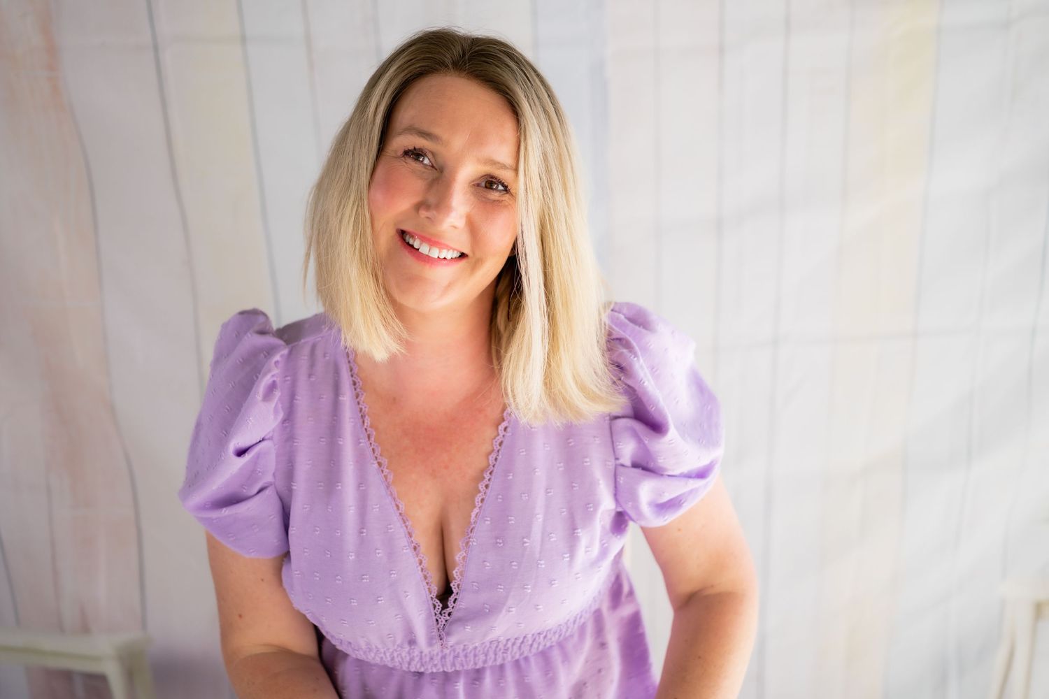 Woman in lavender dress poses for a series of professional headshots against a light background.