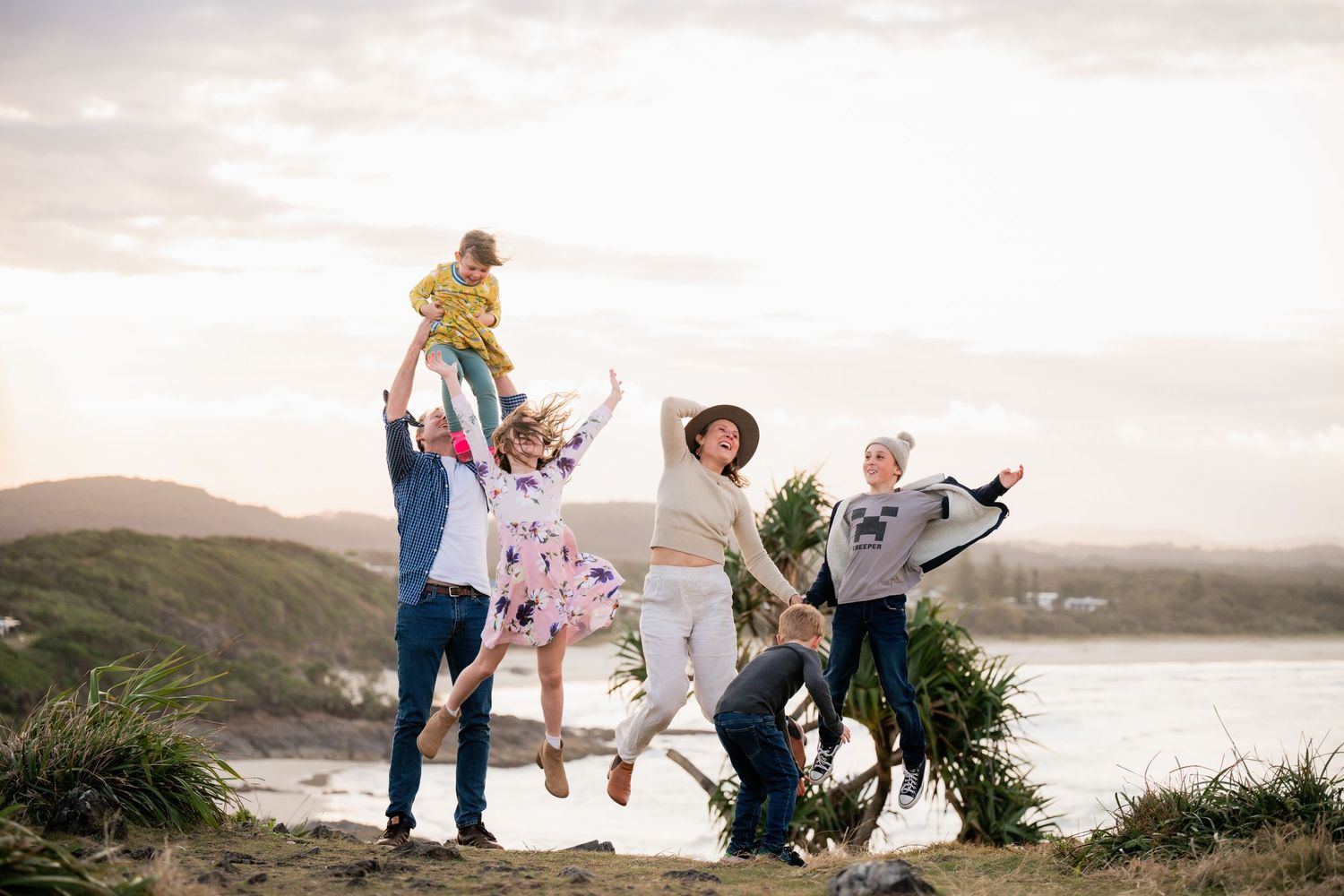 Family portraits captured against a dramatic coastal landscape with cliffs and ocean views.