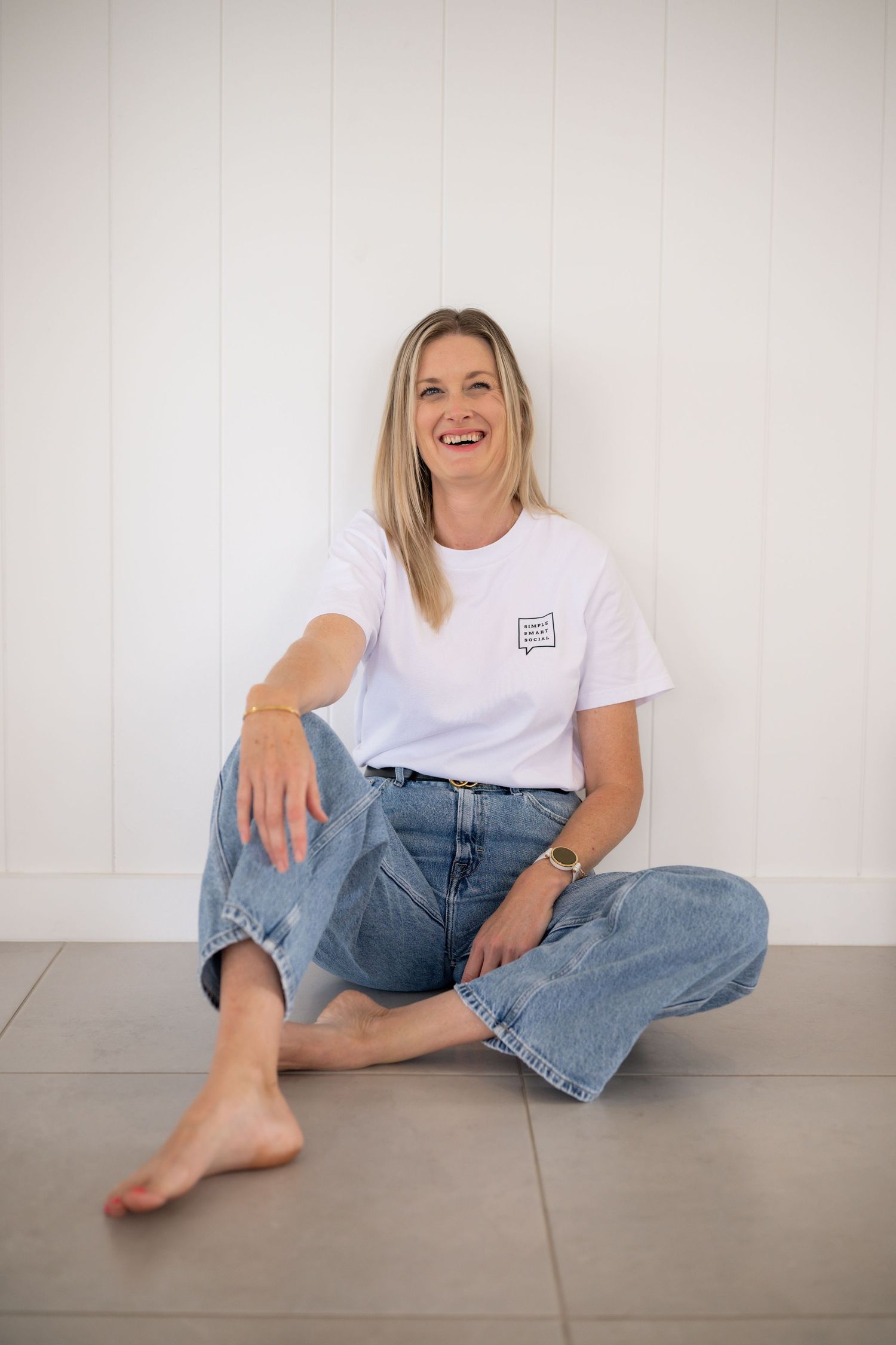 A casual lifestyle photo series showing someone in a white t-shirt and jeans sitting on a gray floor in various relaxed poses.