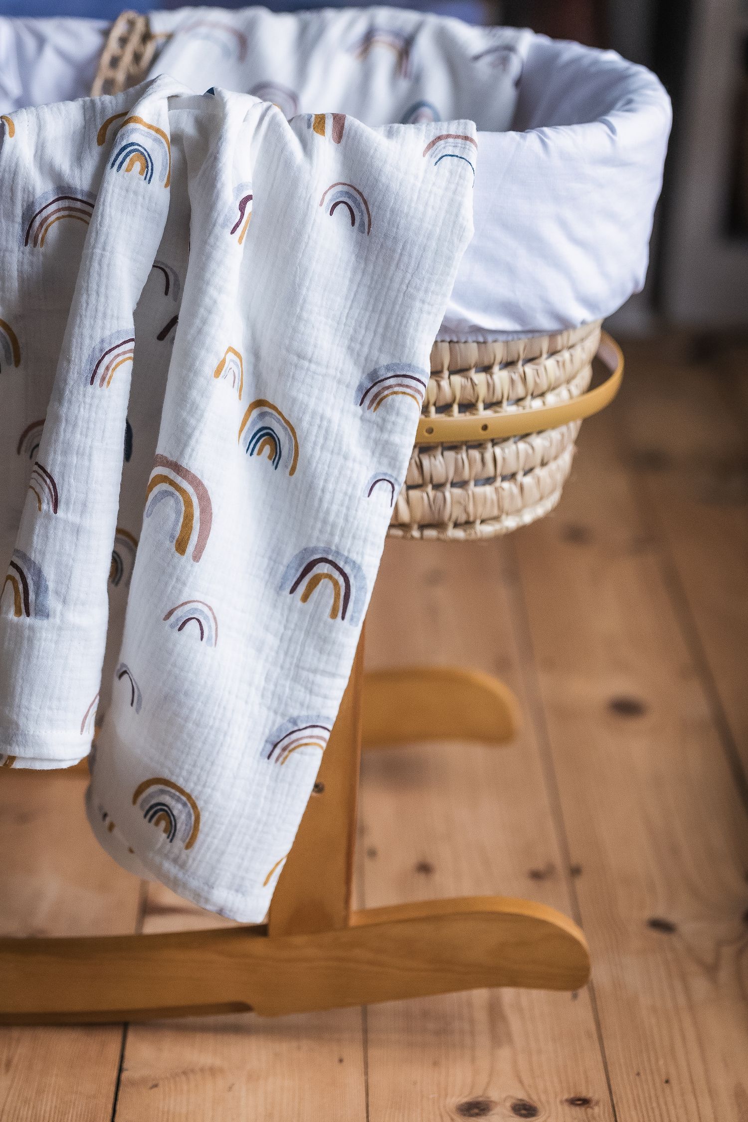 Lifestyle product imagery of a muslin cloth draped across a Moses basket.