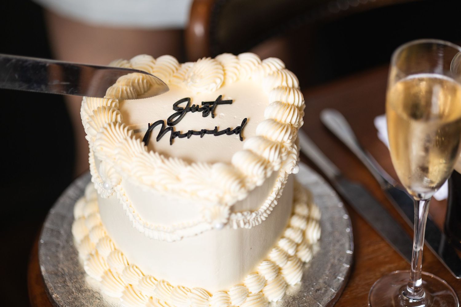 Editorial image of heart shaped wedding cake with black writing on the top saying 