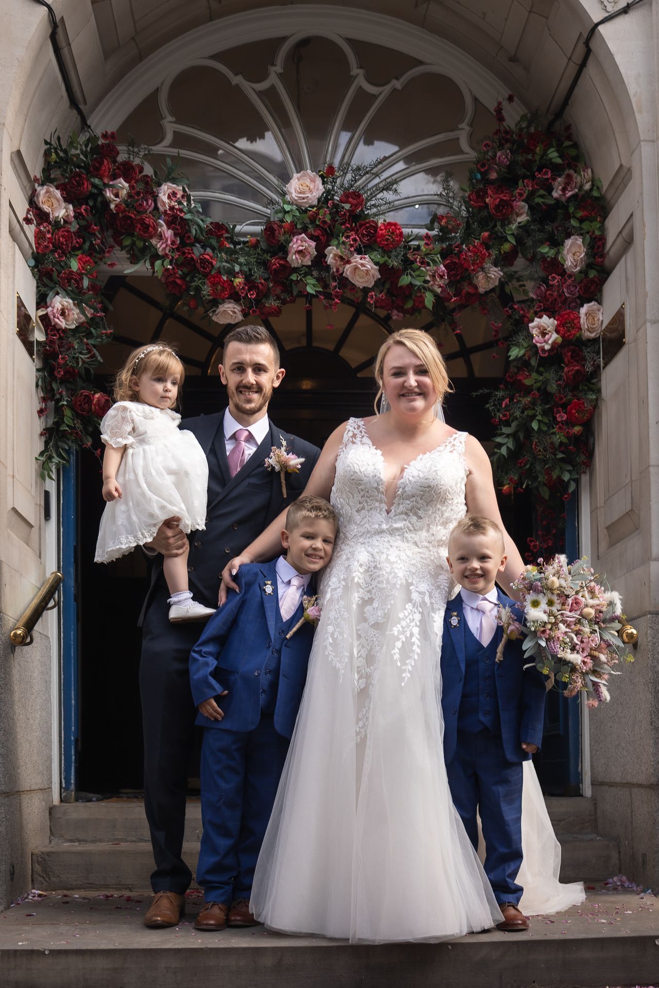 A family photo (of mum, dad and three children) infront of the steps on Chelsea Old Town Hall on their wedding day.