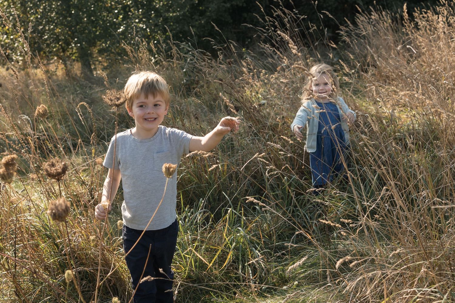 Two young children running through long grass on family photo shoot in St Albans.