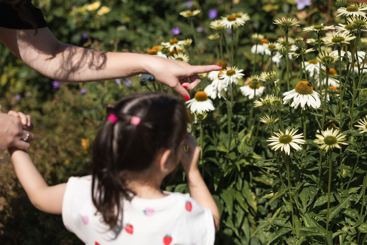 Mother and her daughter looking at a bee that has landed on a giant daisy in Greenwich Park.