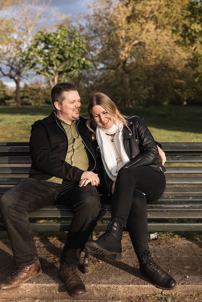 Couple sitting on a bench in the park having a moment together on a pre wedding shoot.