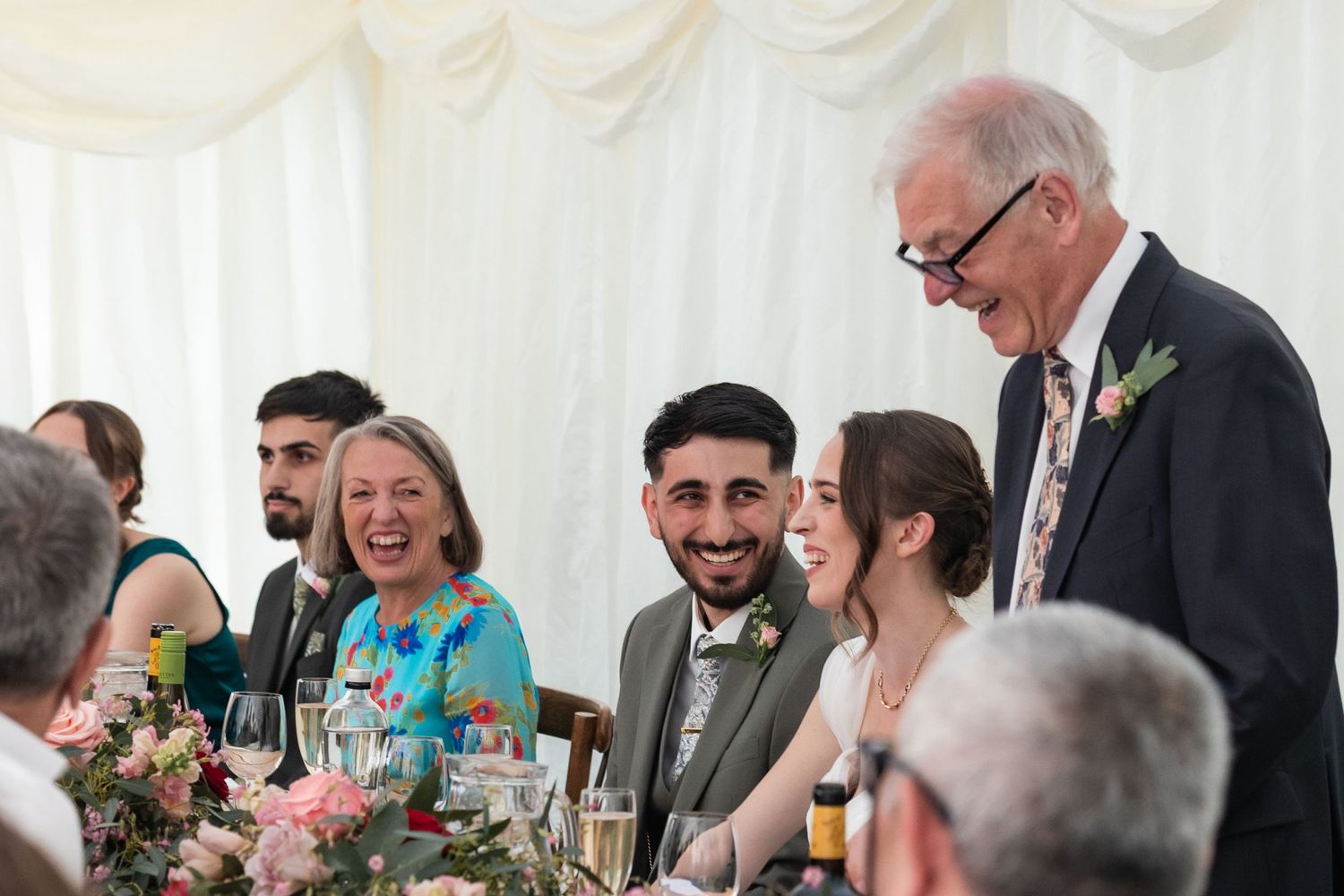 Laughter fills the marquee as the father of the bride delivers his speech on the wedding day.