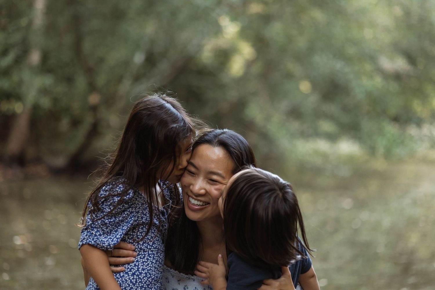 A mum being kissed on both cheeks by her daughter on one side, and her son on the other.
