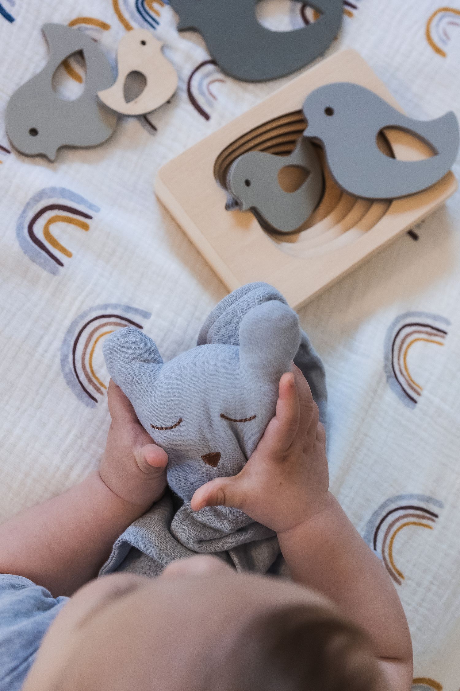 Natural branding imagery showing baby hands playing with  wooden toys and comforter.