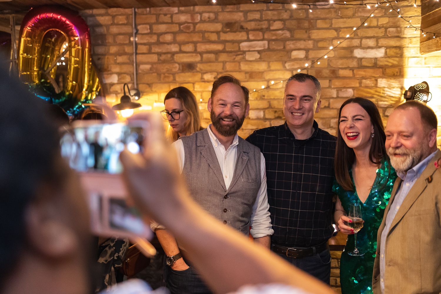 A photo of someone taking a photo of the birthday girl and her guests.