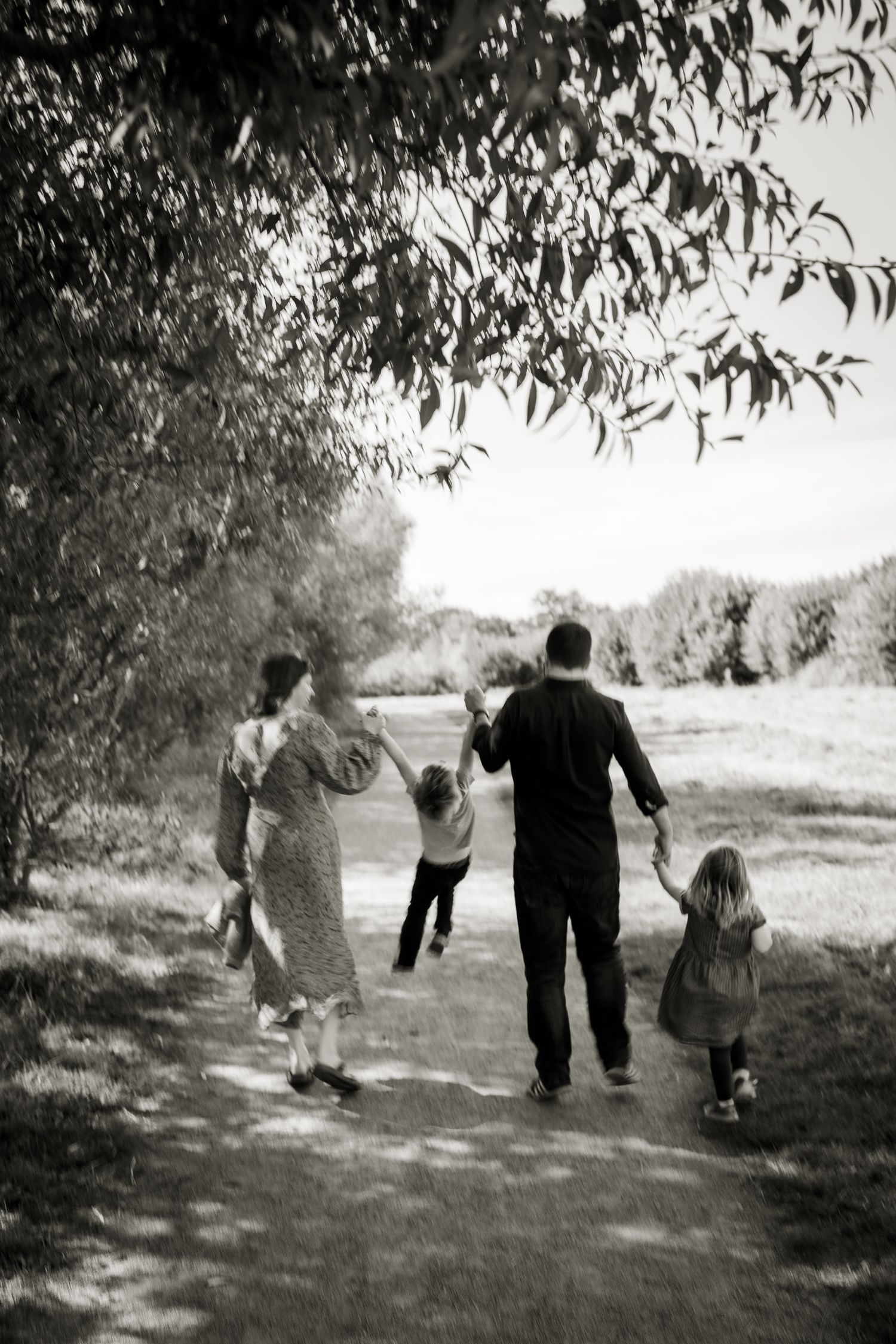 Black and white image of family walking away holding hands during an outdoor family photoshoot in St Albans.