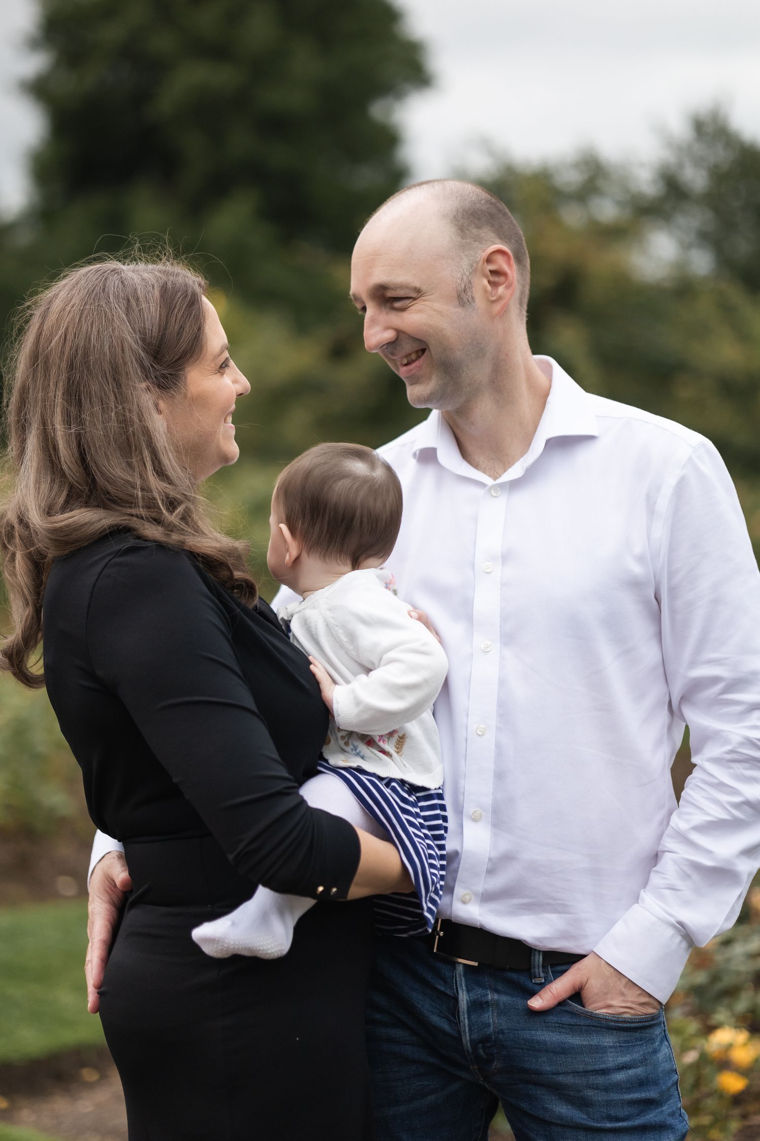A mum and dad looking lovingly at each other, whilst the mum is holding the baby. Lovely candid family shot.