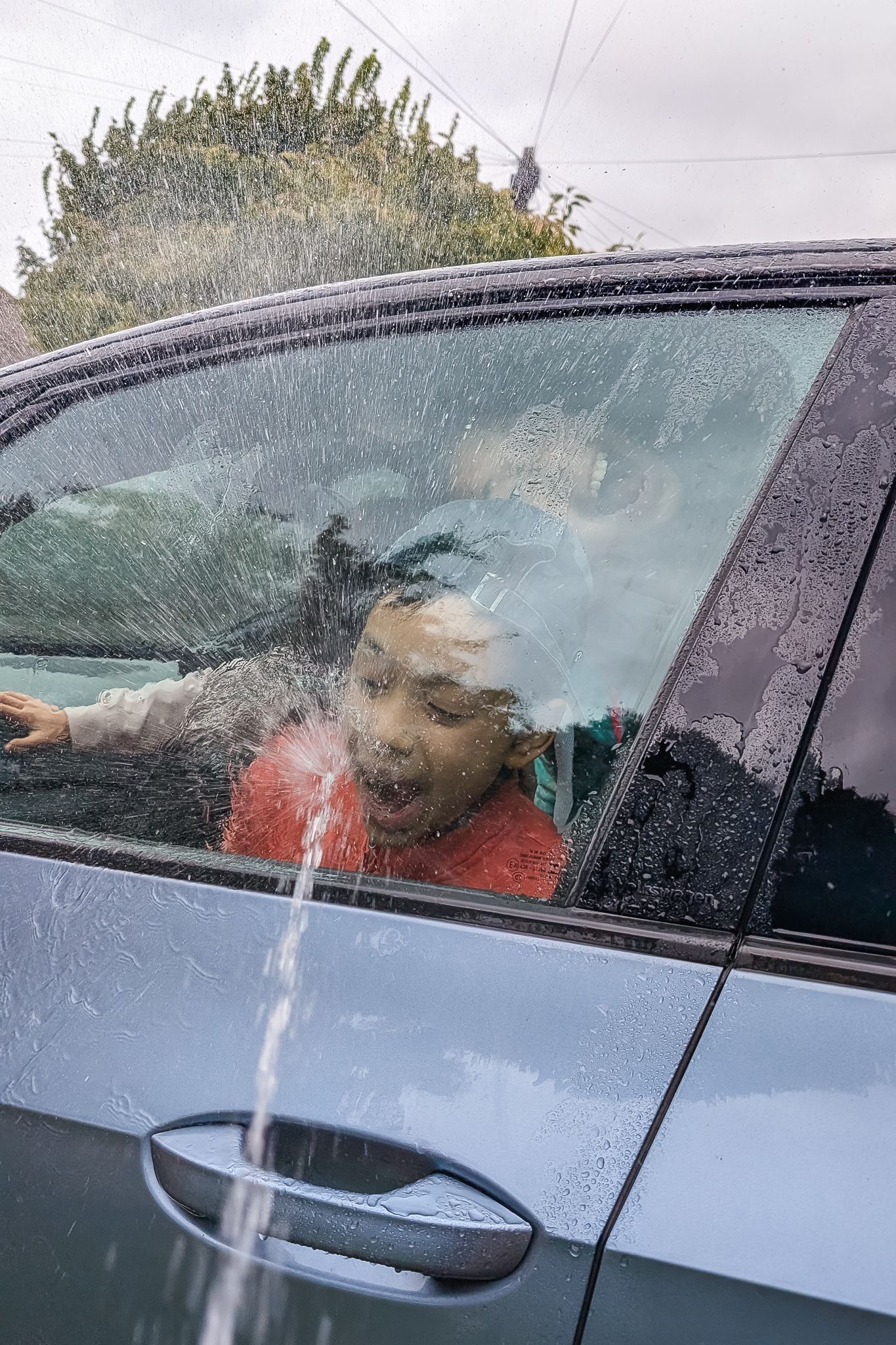 Children pushing their face up against the window and being sprayed with a hose.