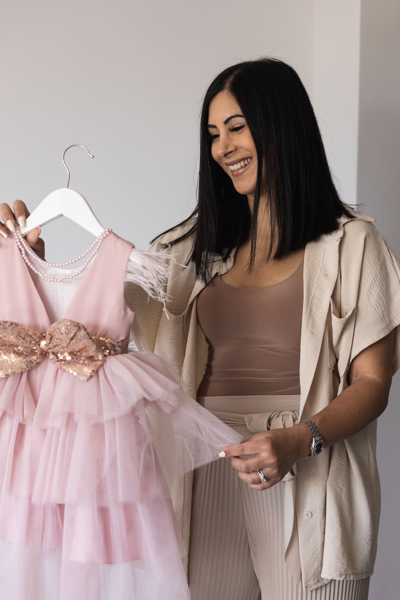 Lifestyle photo captured of the business owner holding one of the beautiful lace flower girl dresses that they sell.
