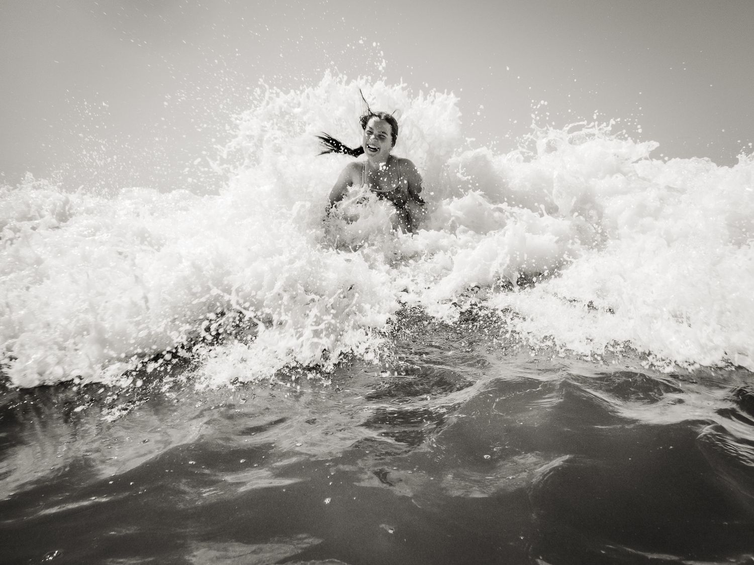 Splashing in the waves on holiday in Bude, black and white image by Jane Nicholson Photography.