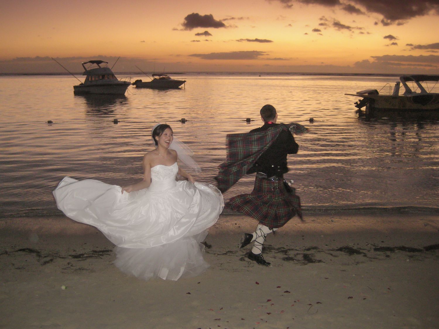 Bride and groom dancing on the beach at golden hour