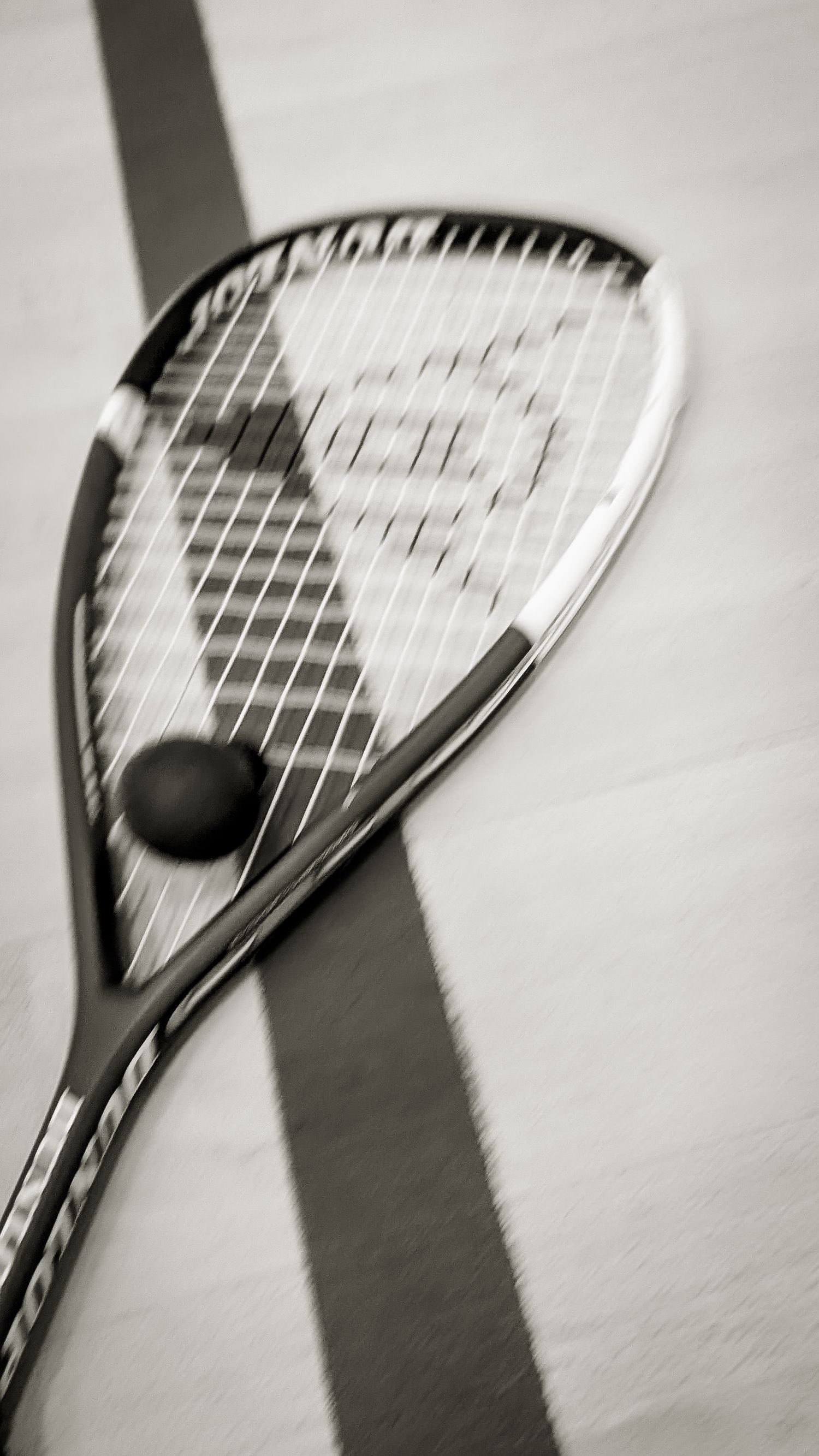 Black and white imagery of squash racket, lines of the court and a squash ball.
