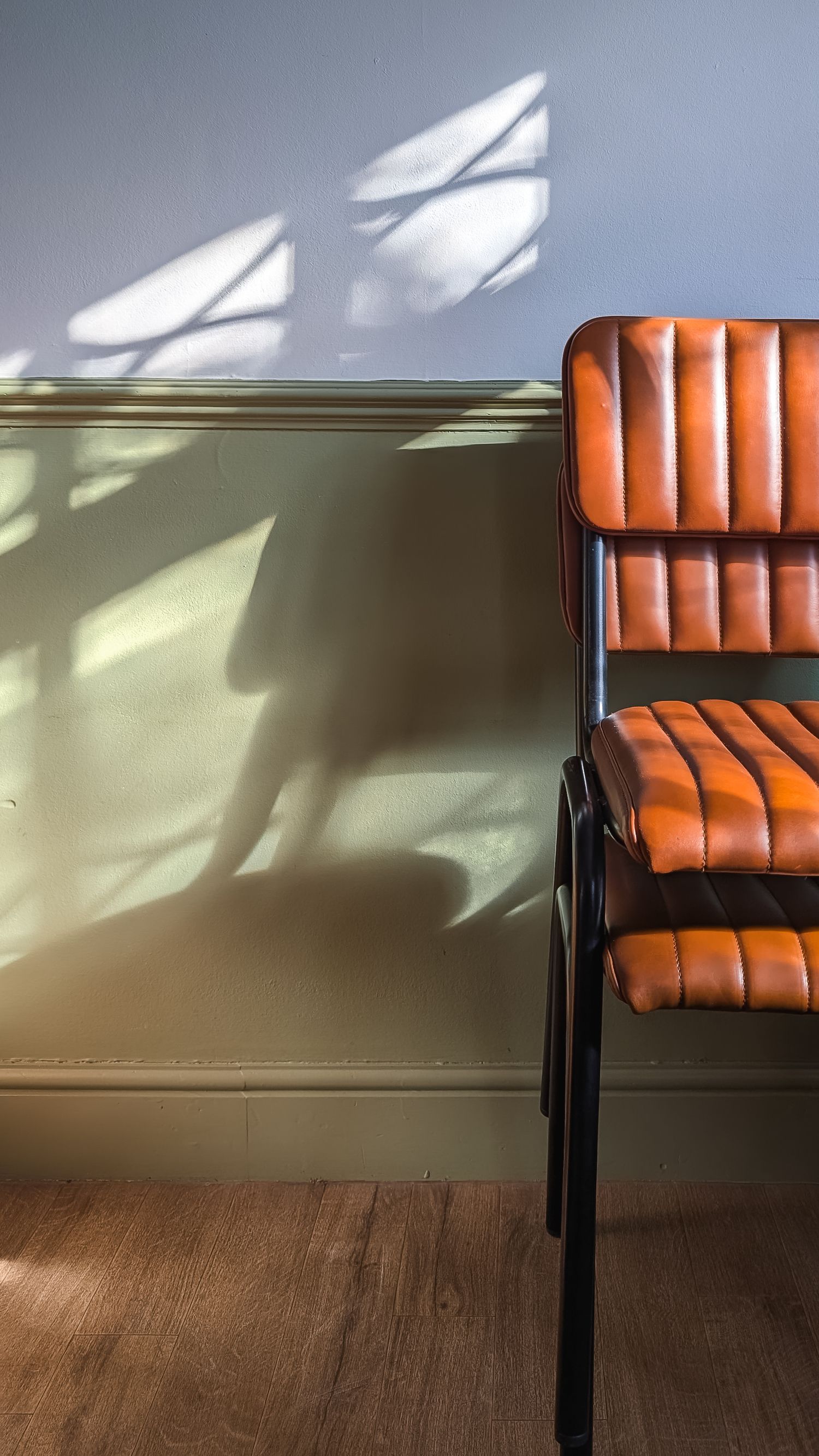 Chairs stacked up, and shadow and window light falling on them.