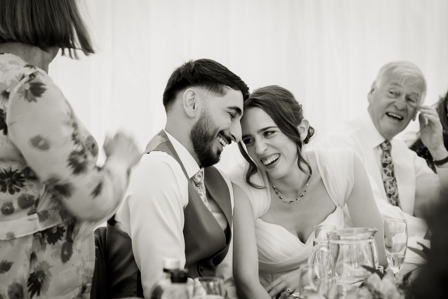 A quiet moment between the bride and groom on their wedding day during the mother of the bride speech.