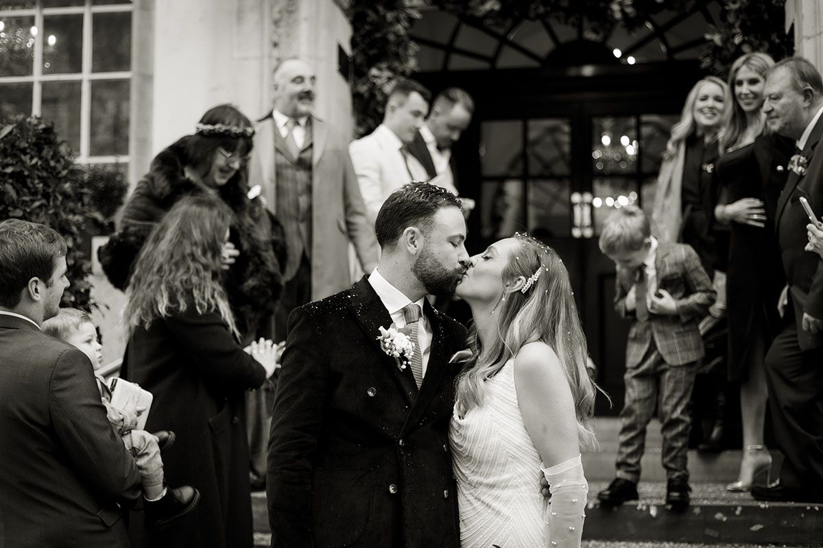 Black and white image of bride and groom kissing on the steps of Chelsea Old Town hall, London
