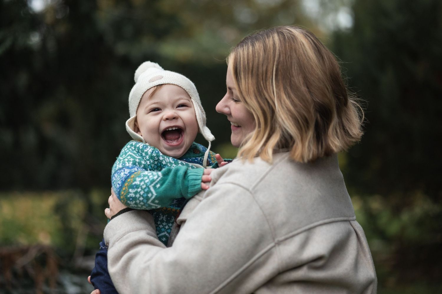 Mum holding toddler laughing at the camera in Friary Park.