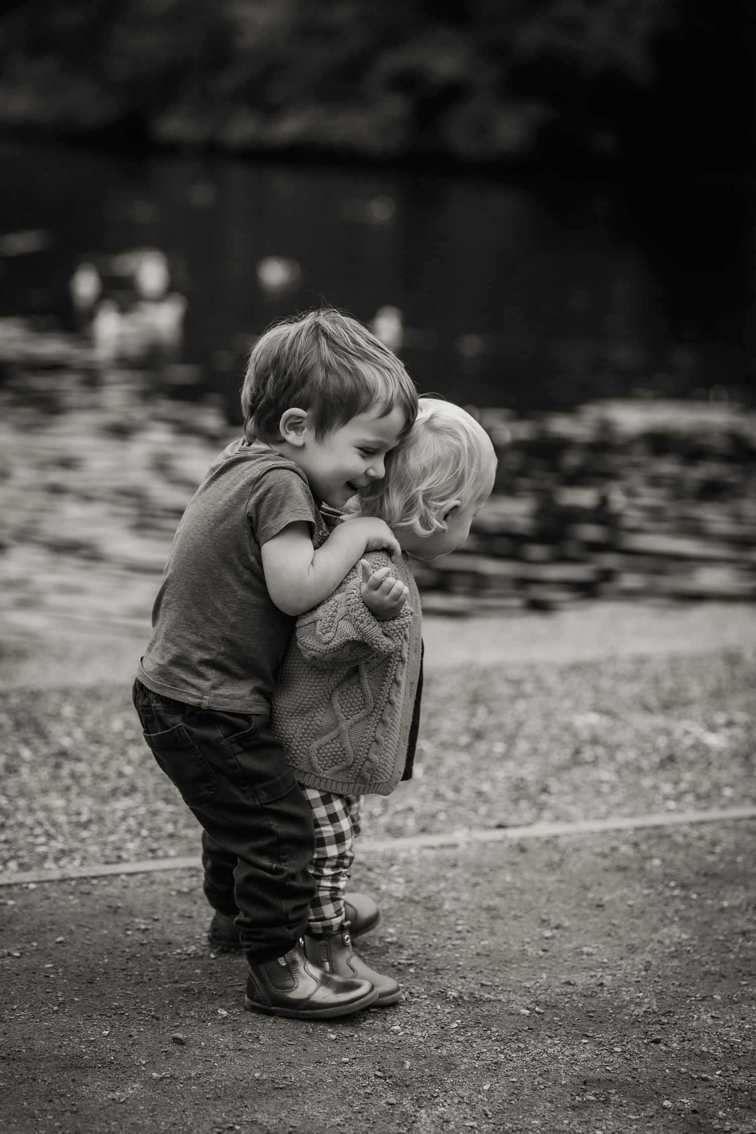 Two young siblings playing together and hugging.
