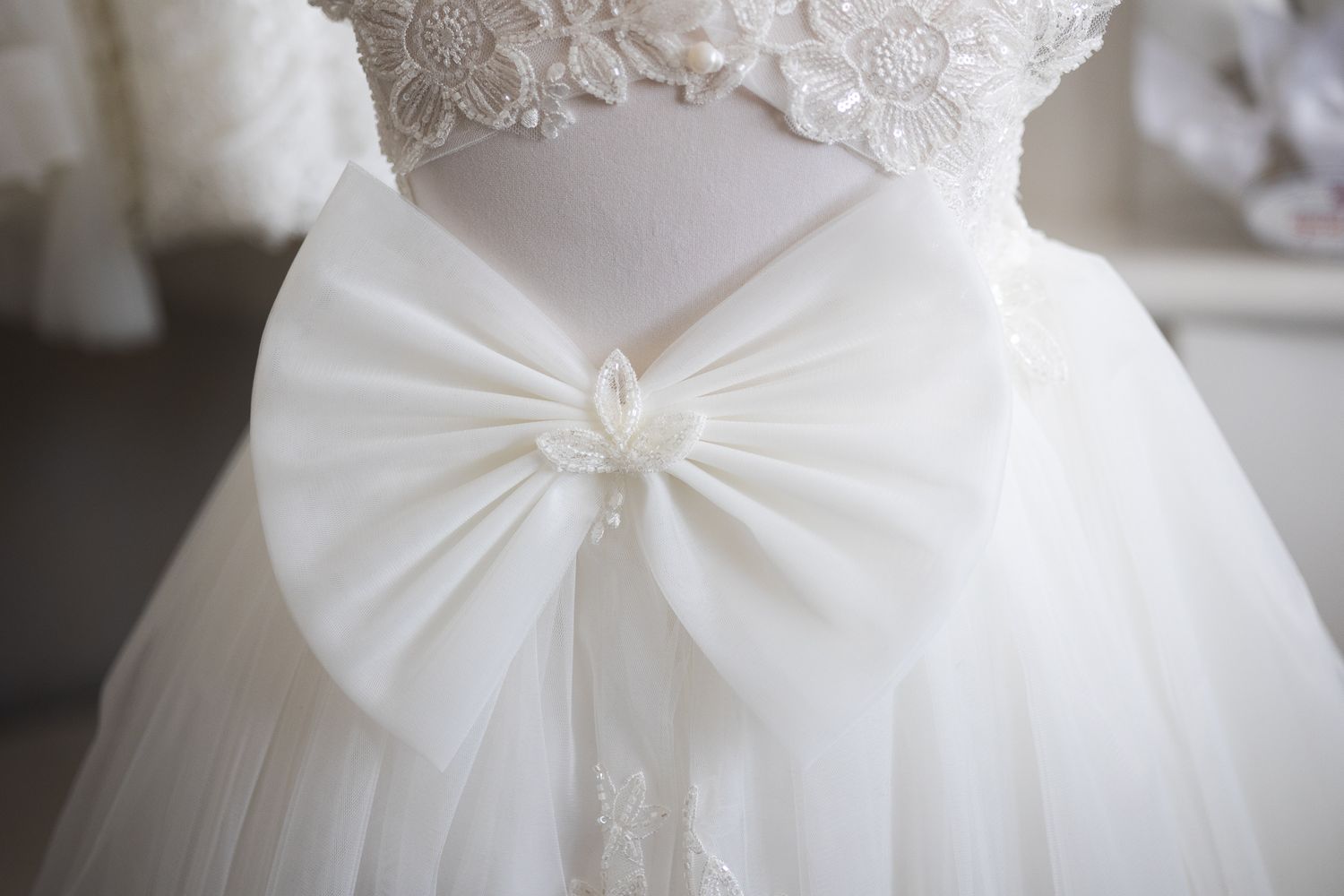 Beautiful close up details of an oversized bow on the back of a Christening dress, in home showroom in Southgate.