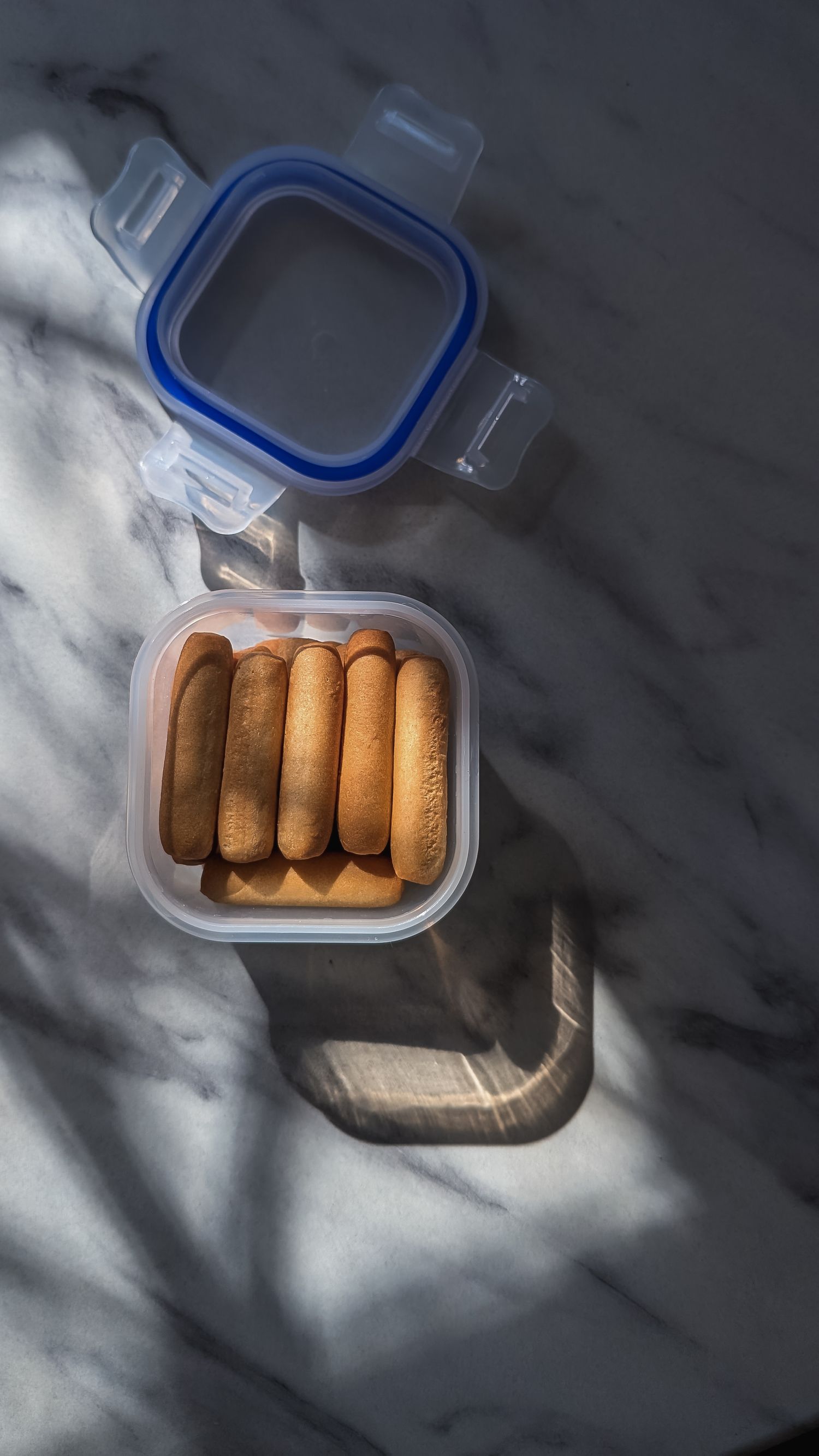 Breadsticks in a container with light and shadows across it.