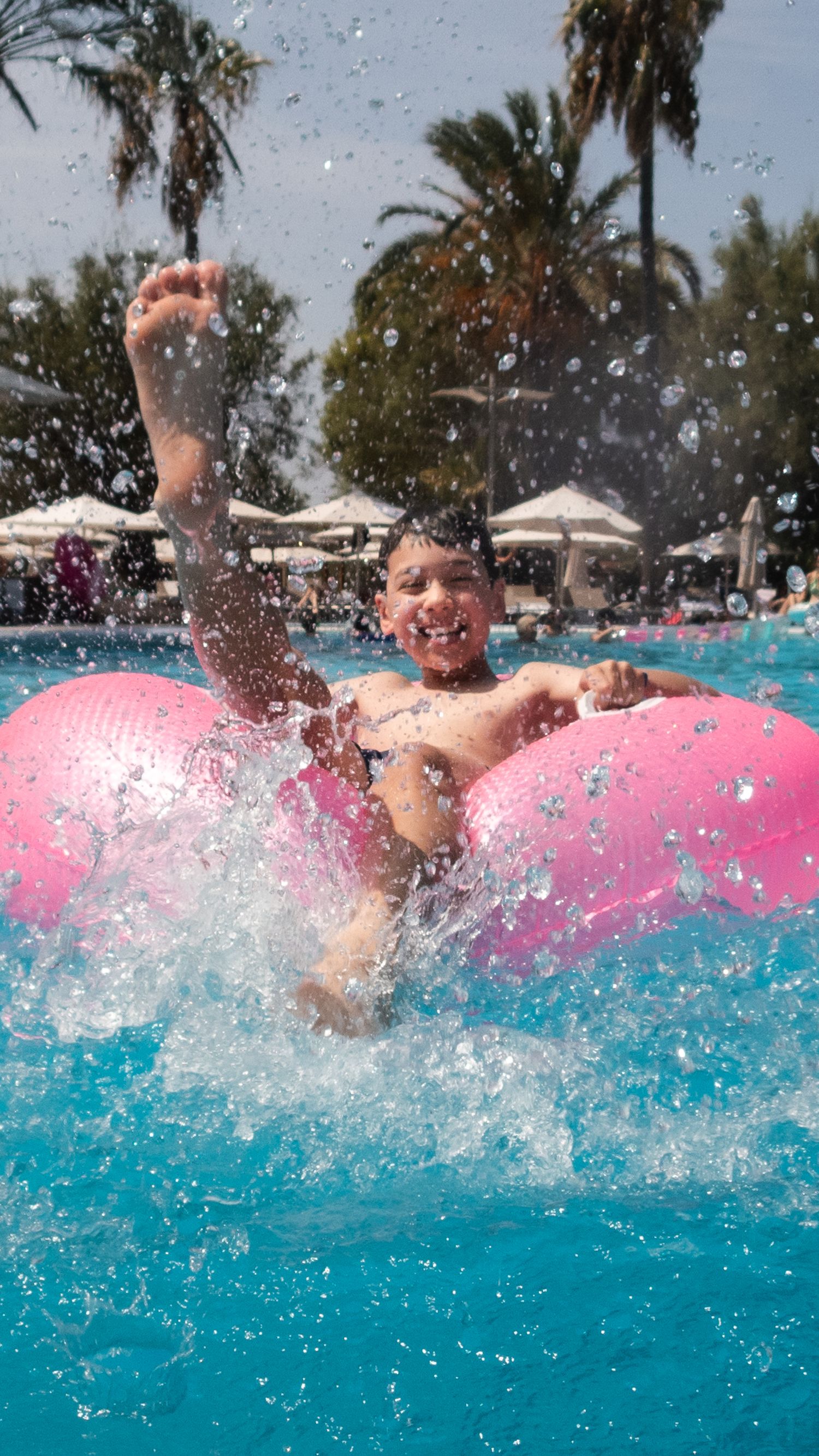 Family photo of children splashing in the pool. Droplets of water creating texture in the image.