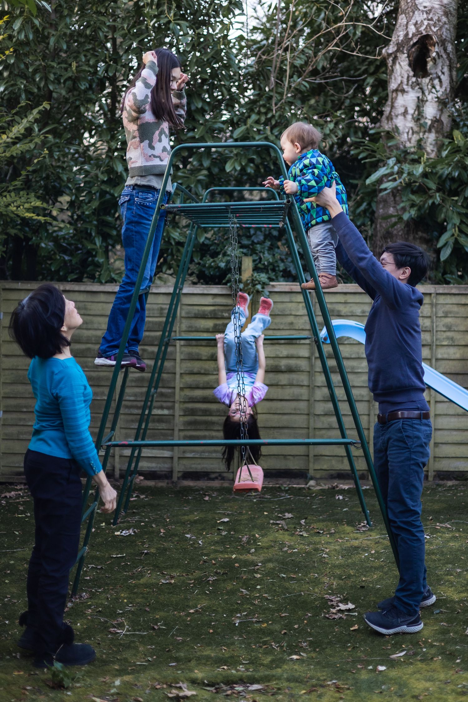 Family playing on a climbing frame in the garden of a North London home.