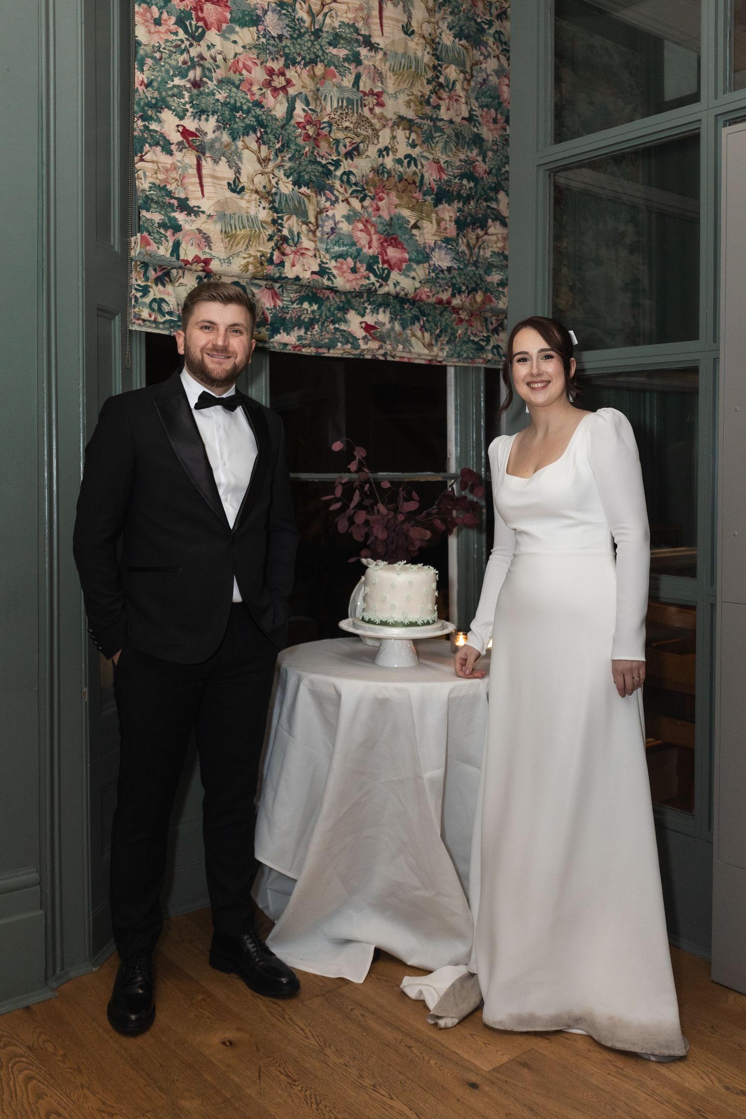 Bride and groom stand next to their wedding cake at their wedding reception following ceremony at London Town Hall wedding.