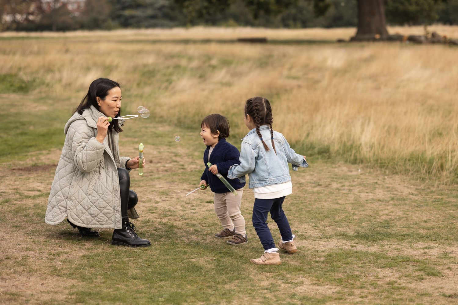 Young family blowing bubbles in Grovelands park