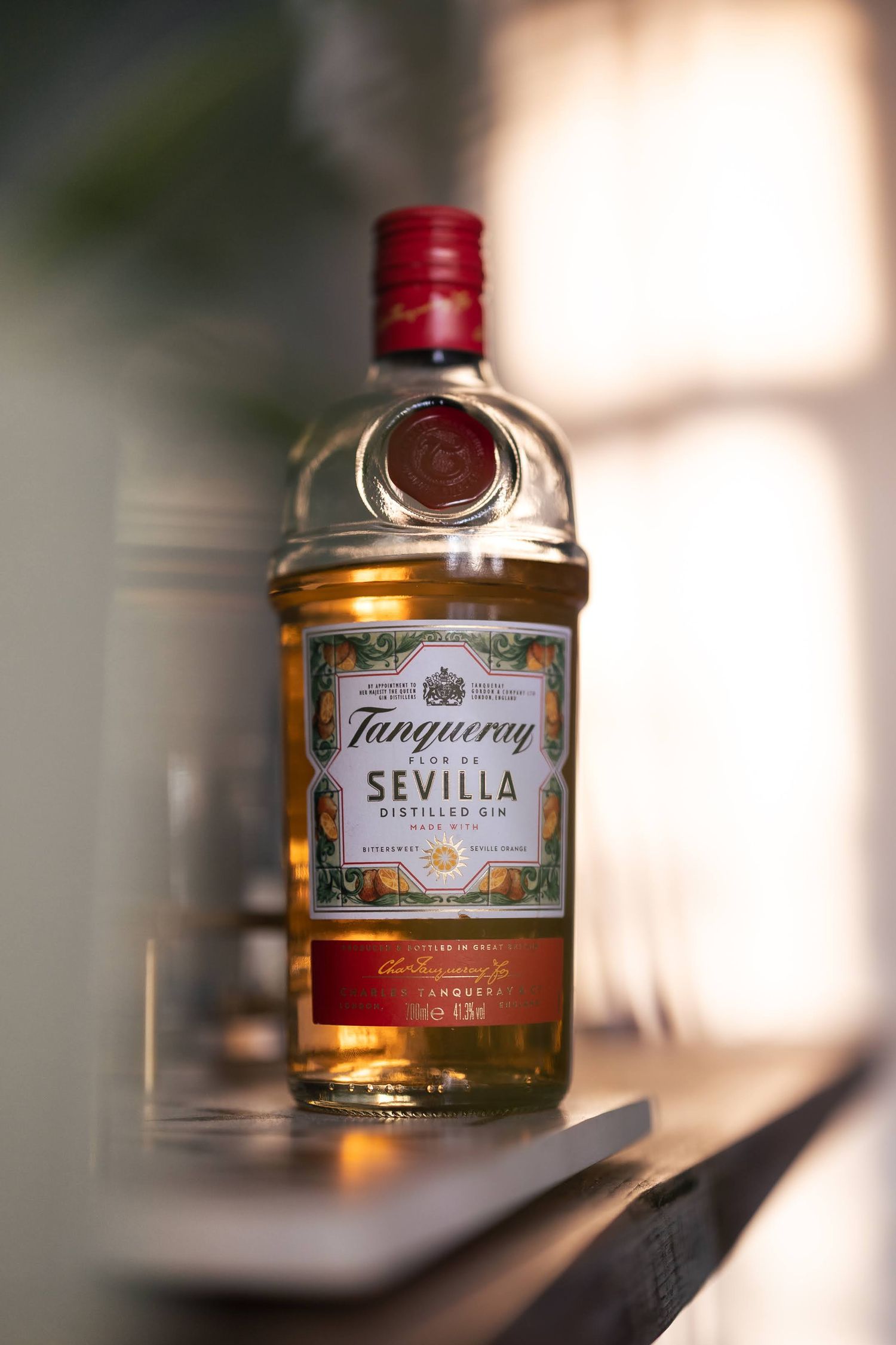 Tanqueray Seville orange gin in the sunshine. With shadows and light in the background, blurry bokeh taken with 50mm 1.2 lens.