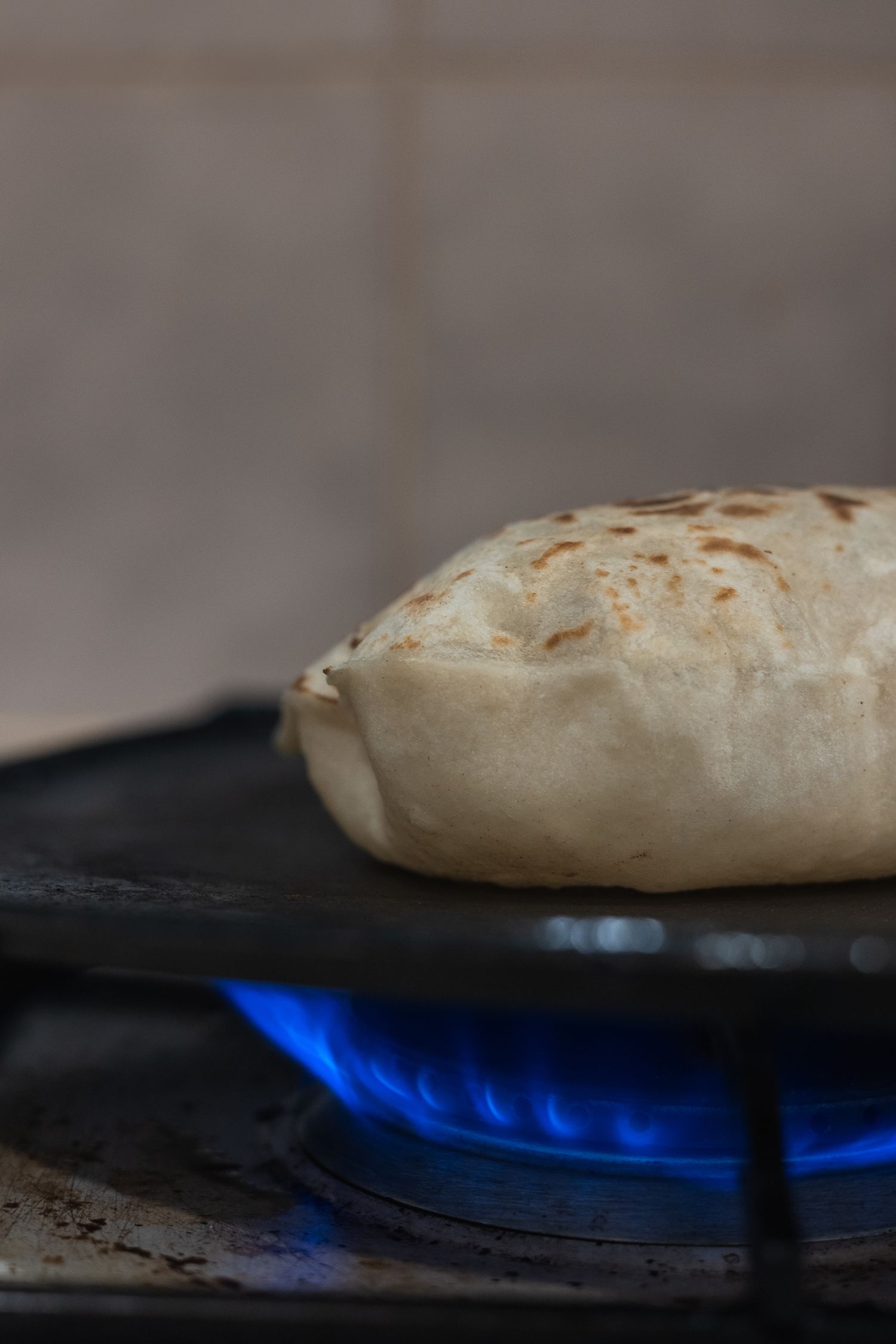 Puffed up roti being cooked on flame.