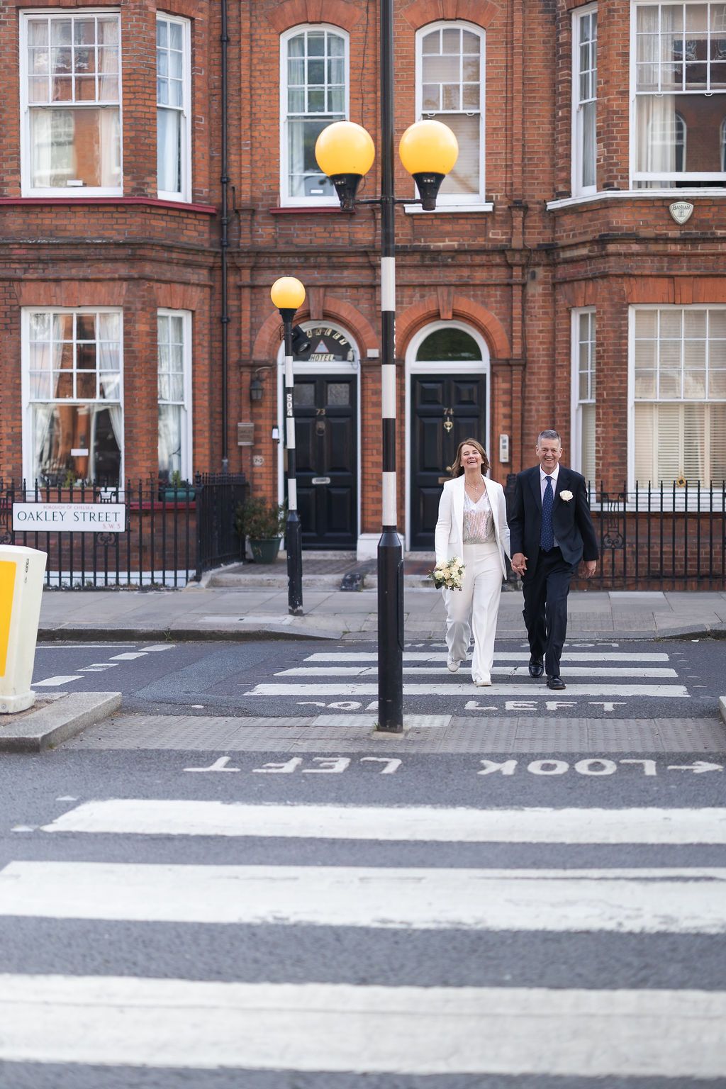 London Street photography including bride and groom walking across zebra crossing after London ceremony.