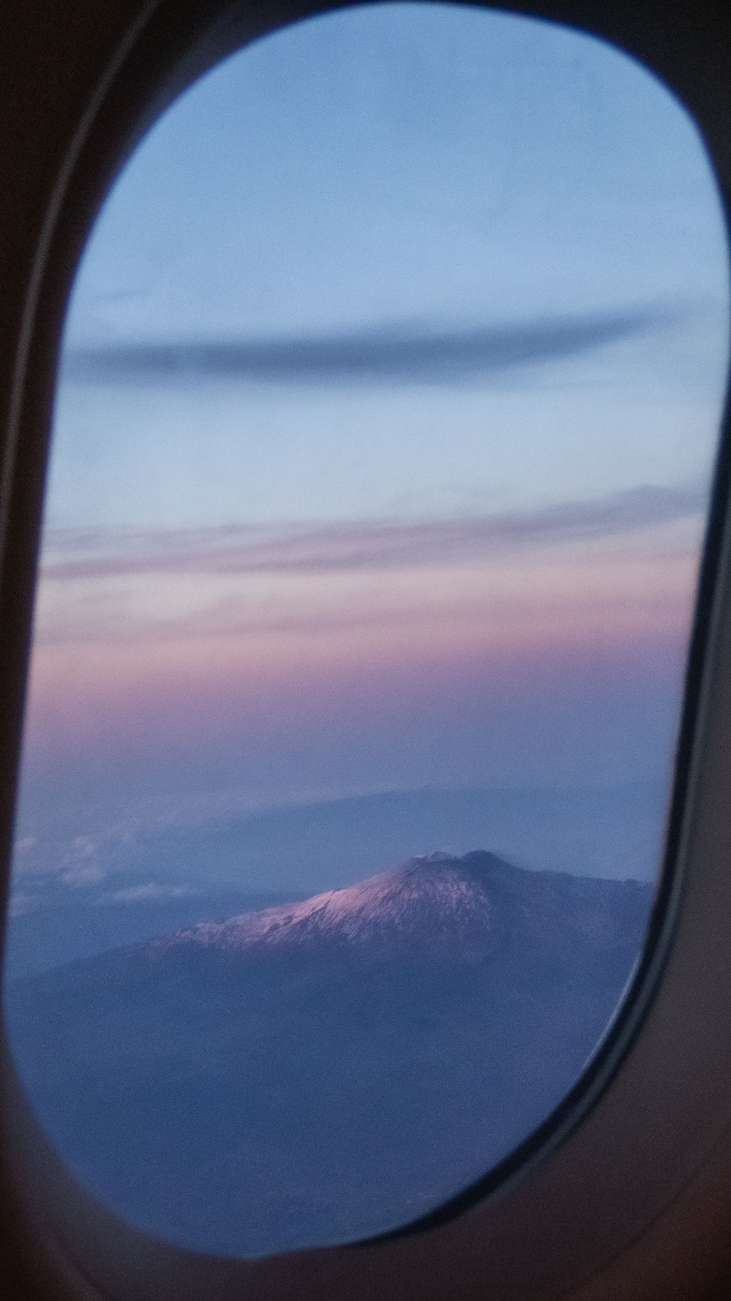 A view from the plane window of the sun setting behind Mount Etna.